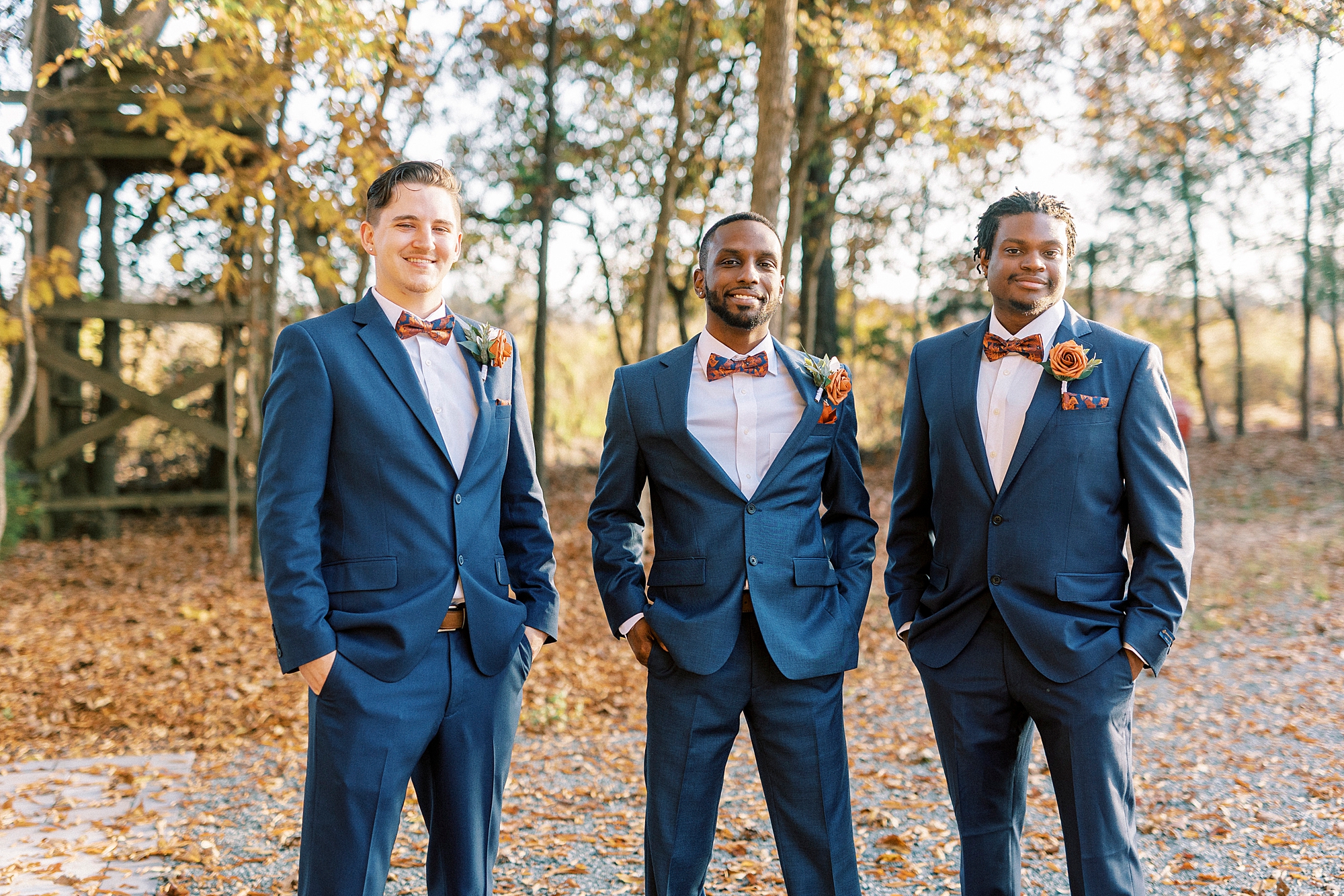 groom stands with hands in pockets of navy suit by groomsmen 