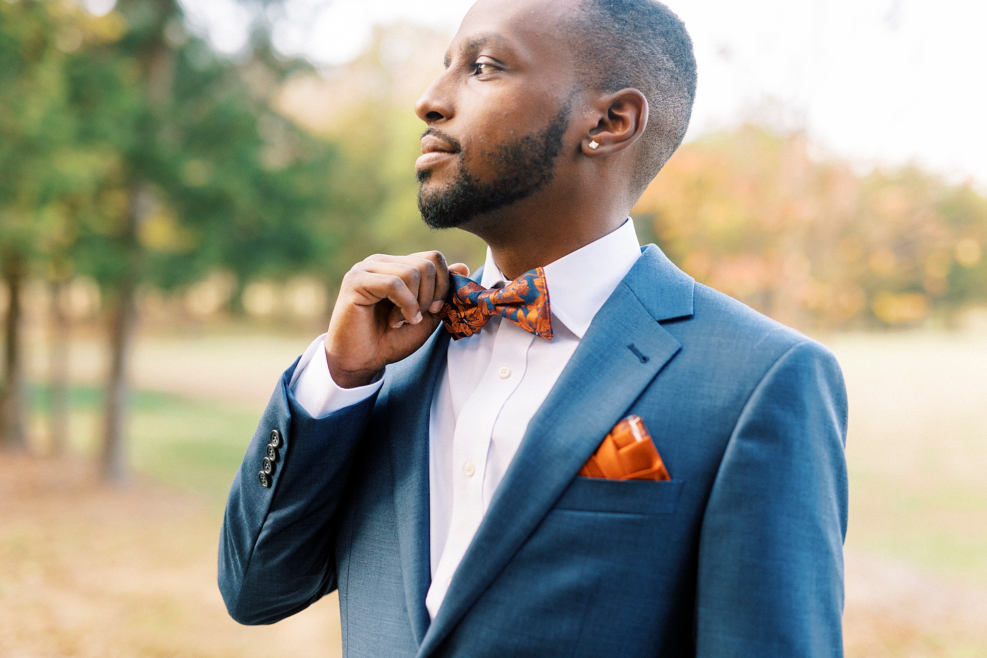 black man adjusts orange and blue tie in navy suit jacket at Bella Terra 