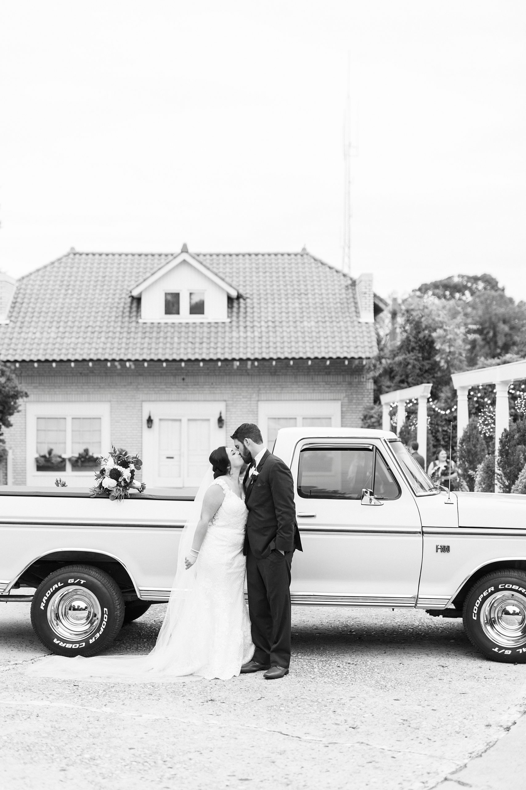 newlyweds kiss beside resorted blue Ford truck