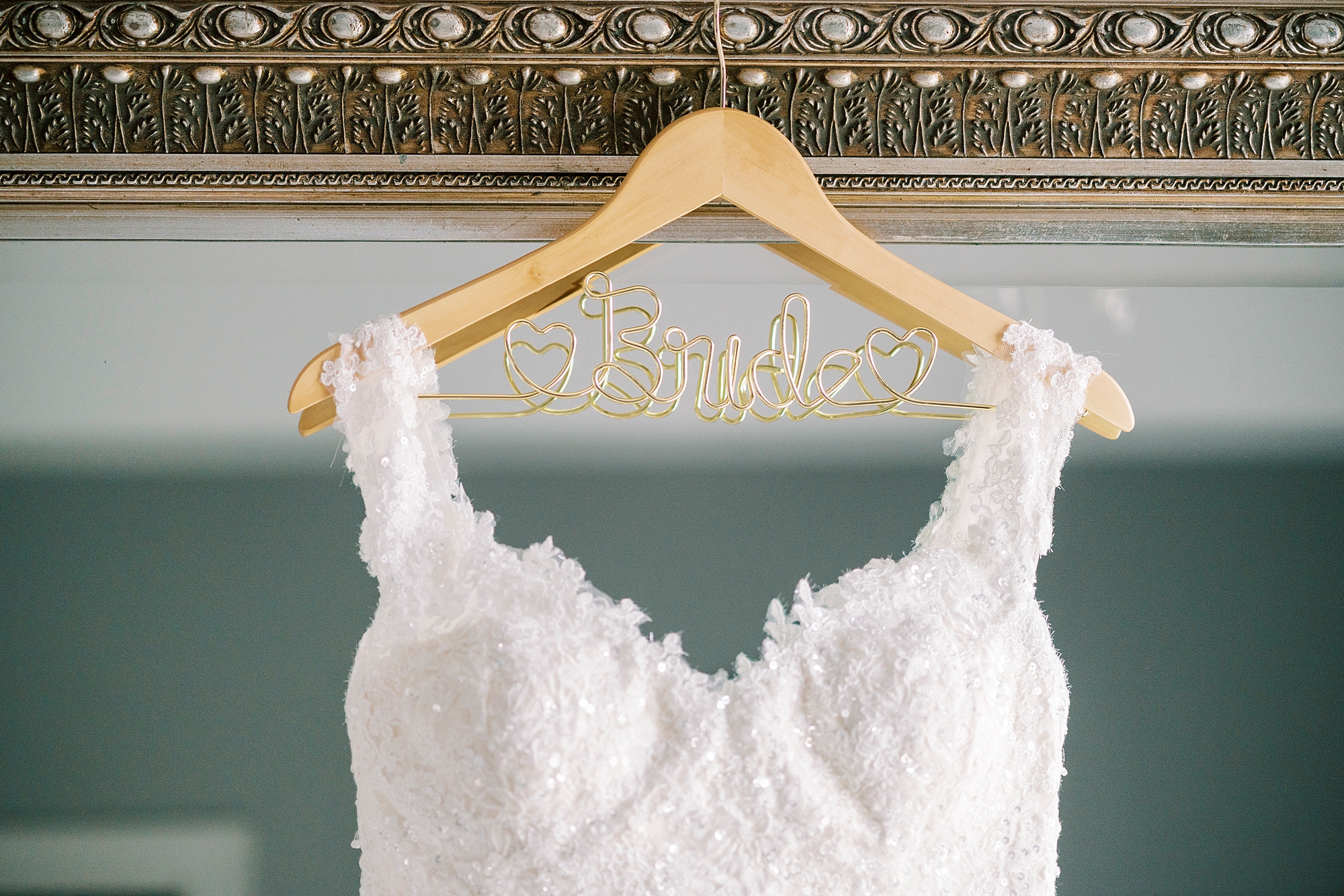 wedding gown hangs on wooden "bride" hanger 