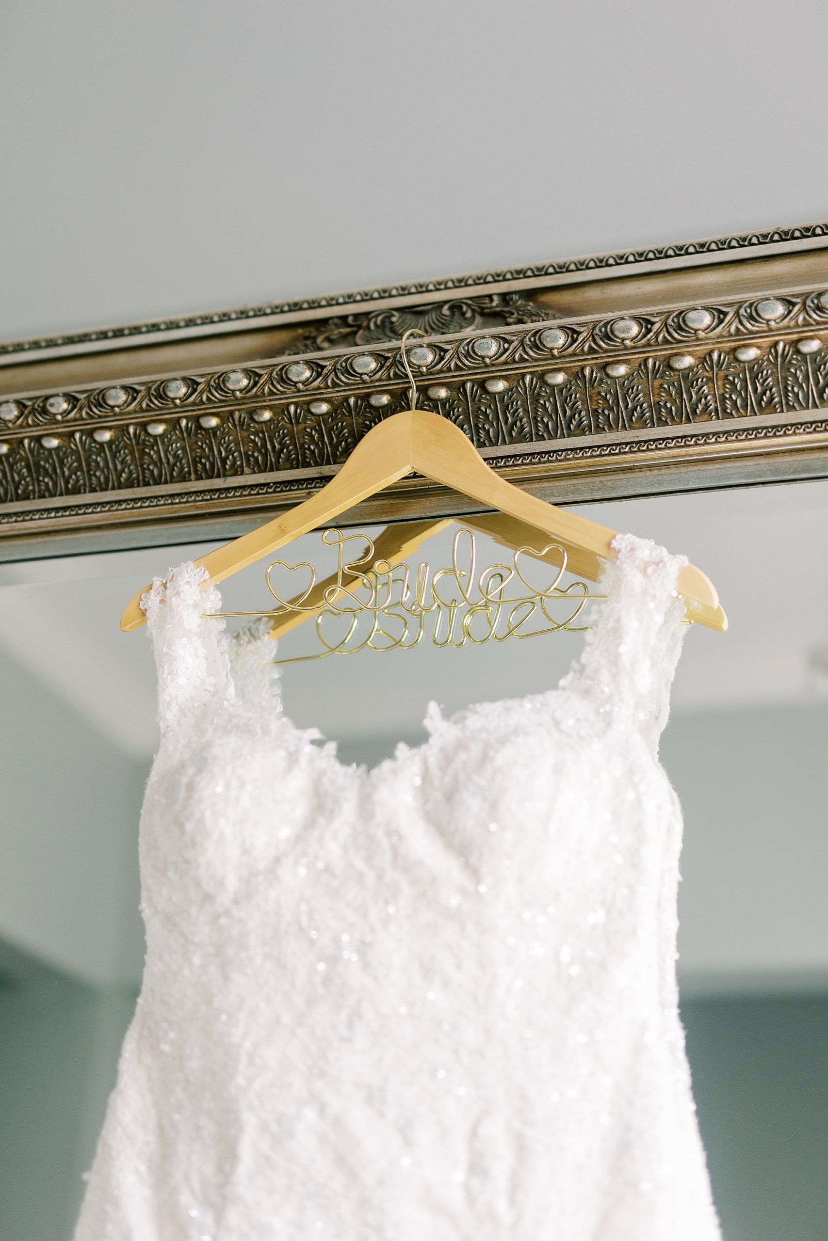 wedding dress hangs on gold mirror in bridal suite at Separk Mansion 