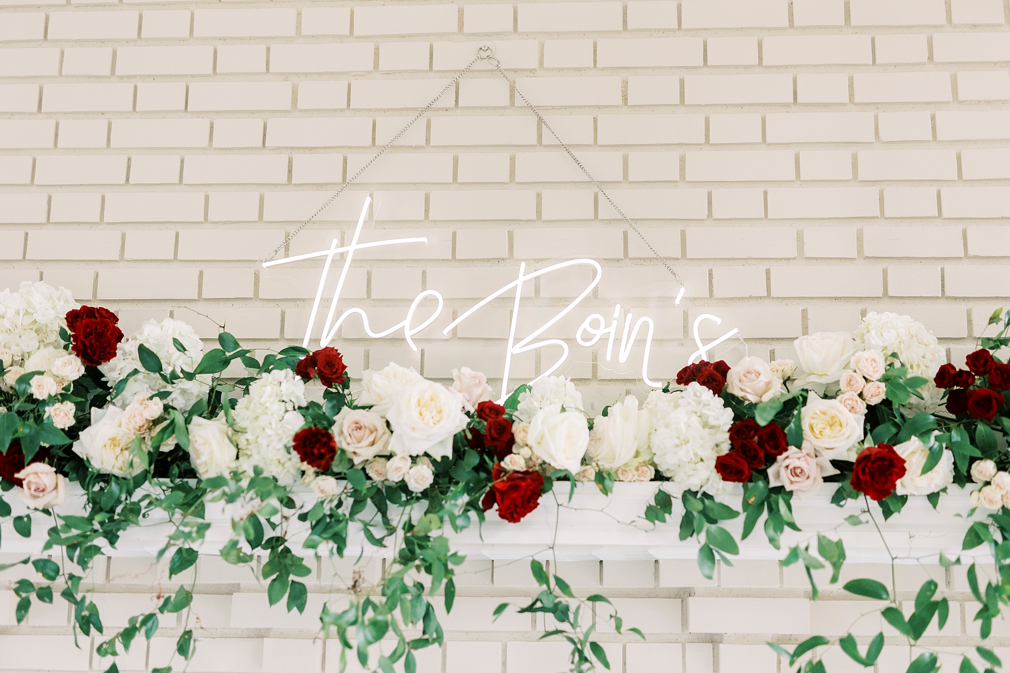 neon sign behind white and red floral display 
