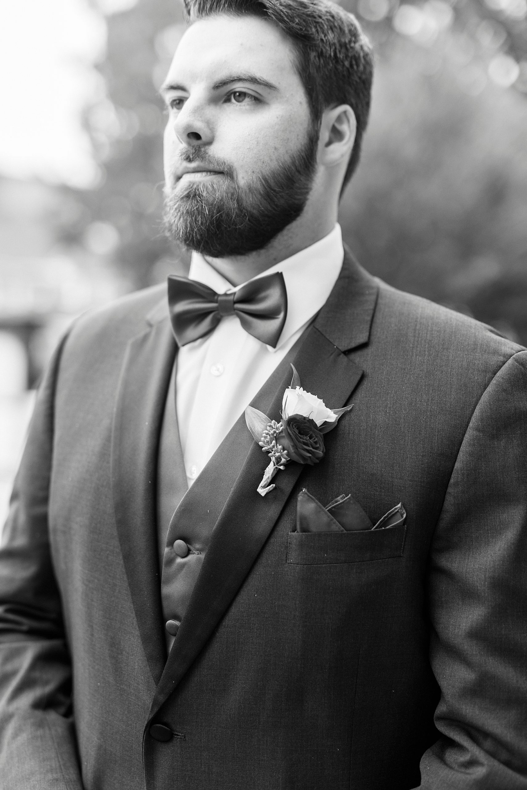 groom stands in classic suit with simple boutonniere 