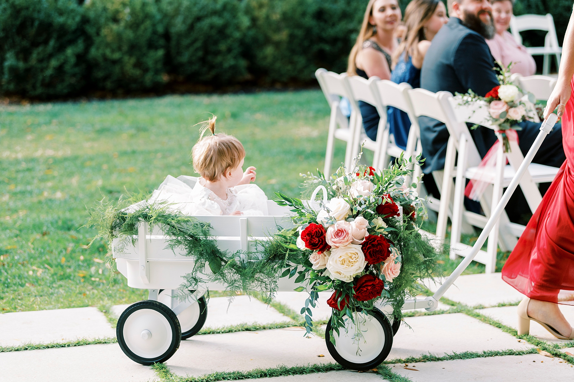 flower girl rolled down aisle in wagon with pink and red flowers 