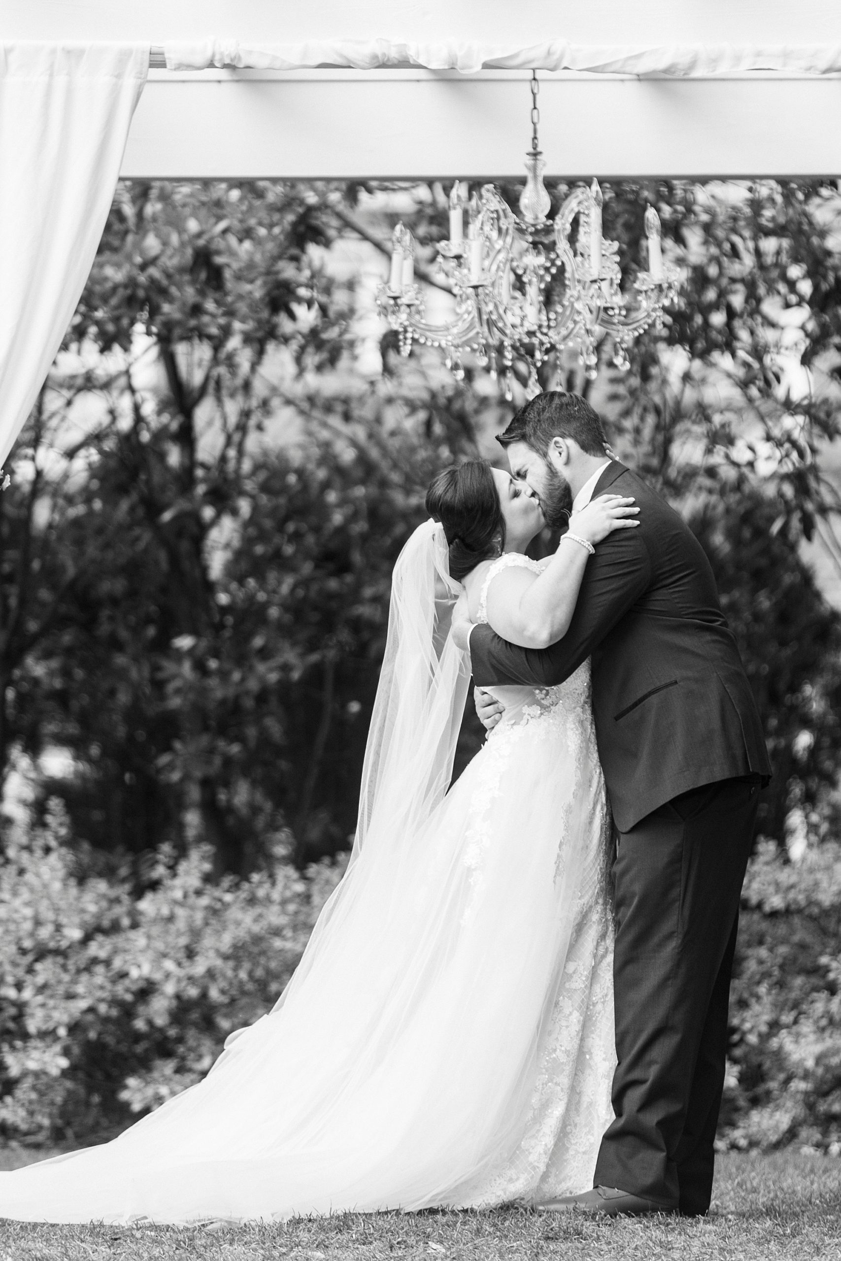 bride and groom kiss under arbor during outdoor wedding ceremony at Separk Mansion