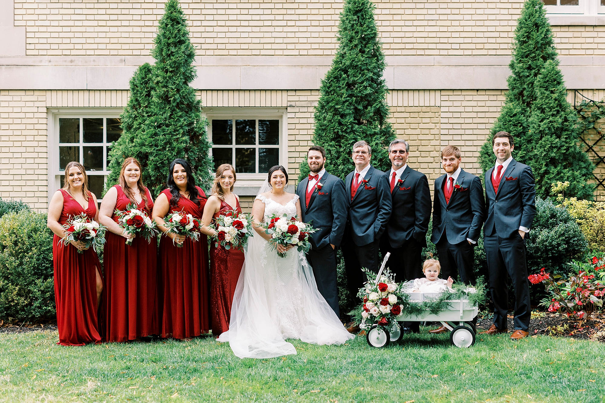 bride and groom pose with wedding party in red and navy