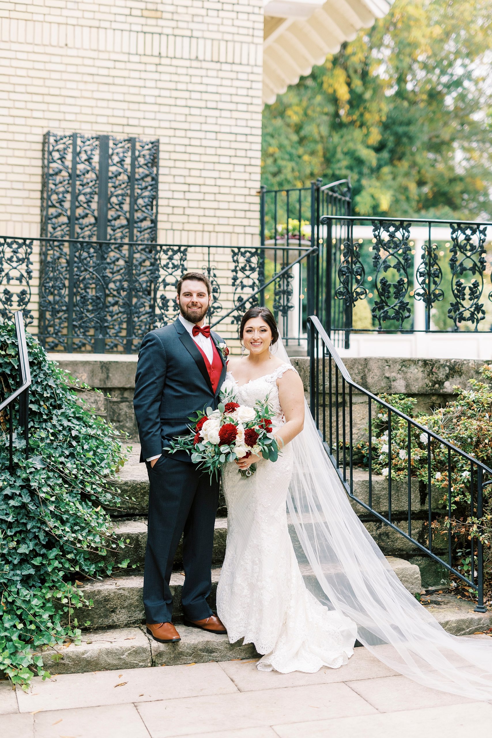 bride and groom stand in front of wrought iron fence at Separk Mansion