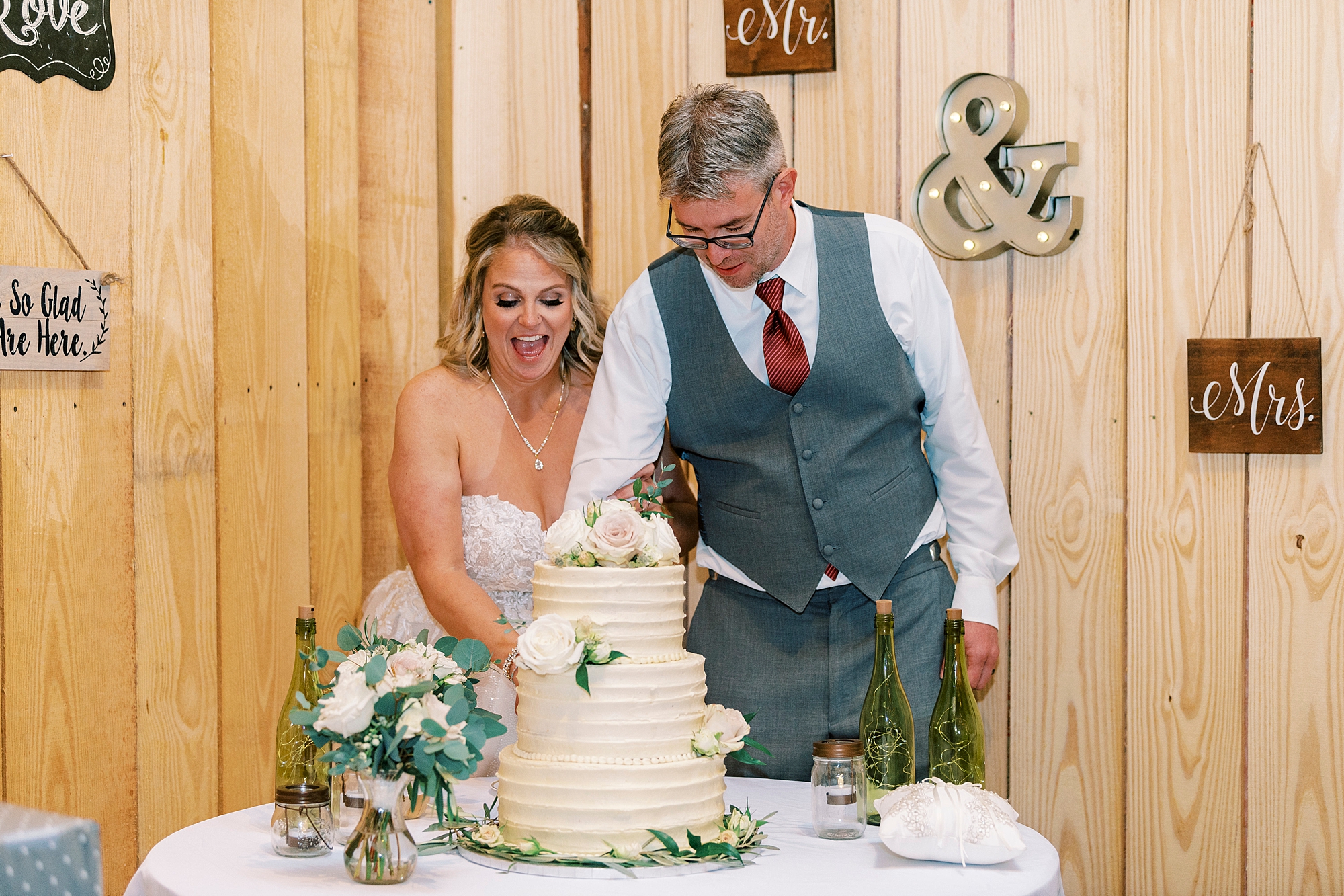 bride laughs while cutting cake at the Gin at Aw Shucks Farm