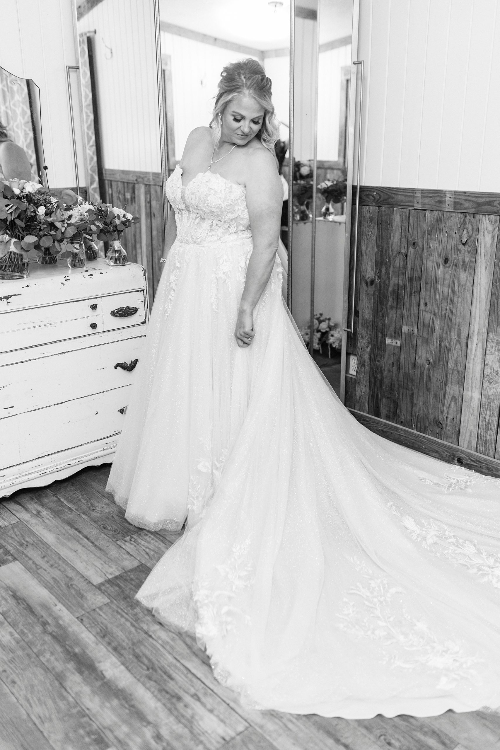 bride stands by mirror in bridal suite at the Gin at Aw Shucks Farm