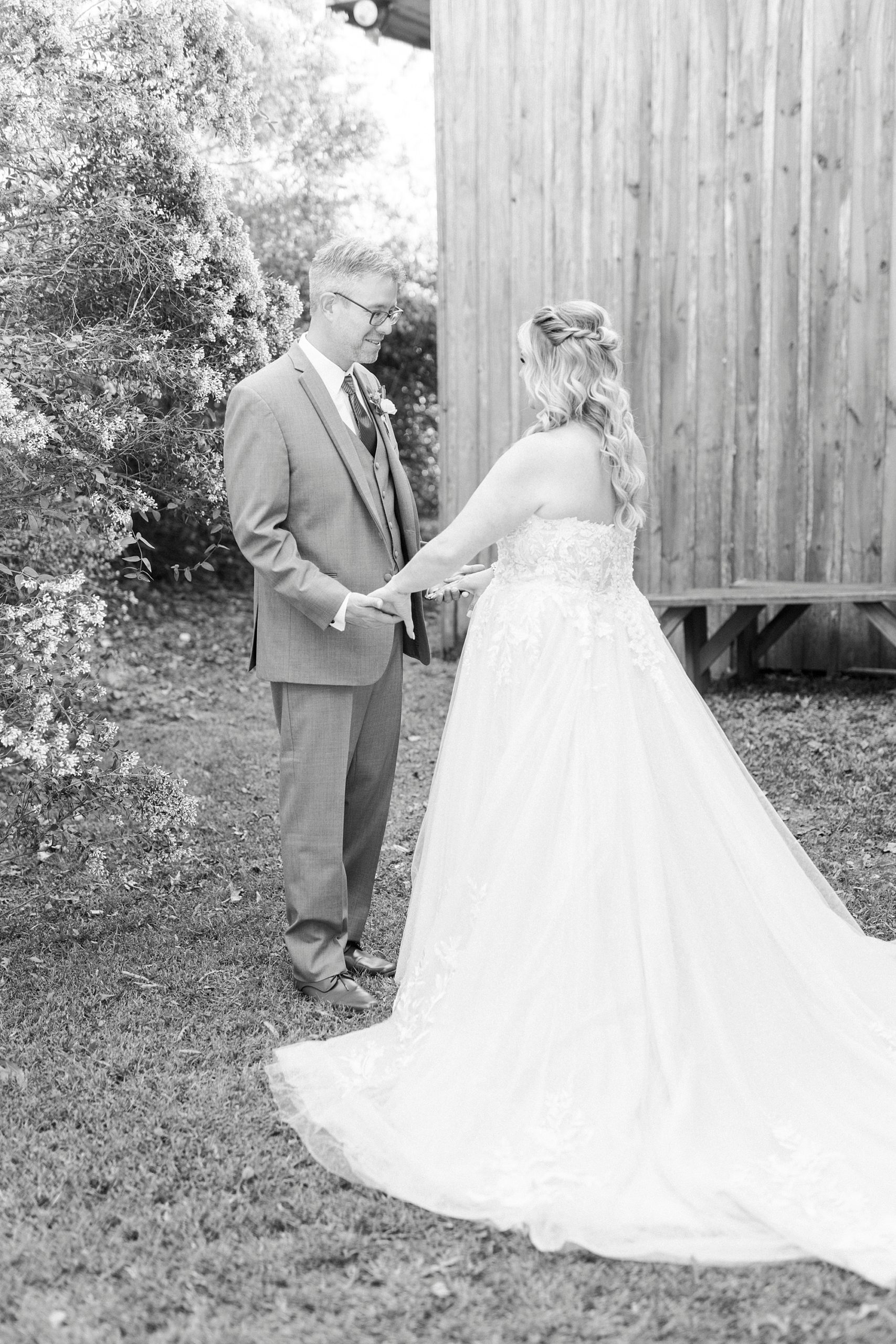 groom looks at bride's dress during first look at the Gin at Aw Shucks Farm