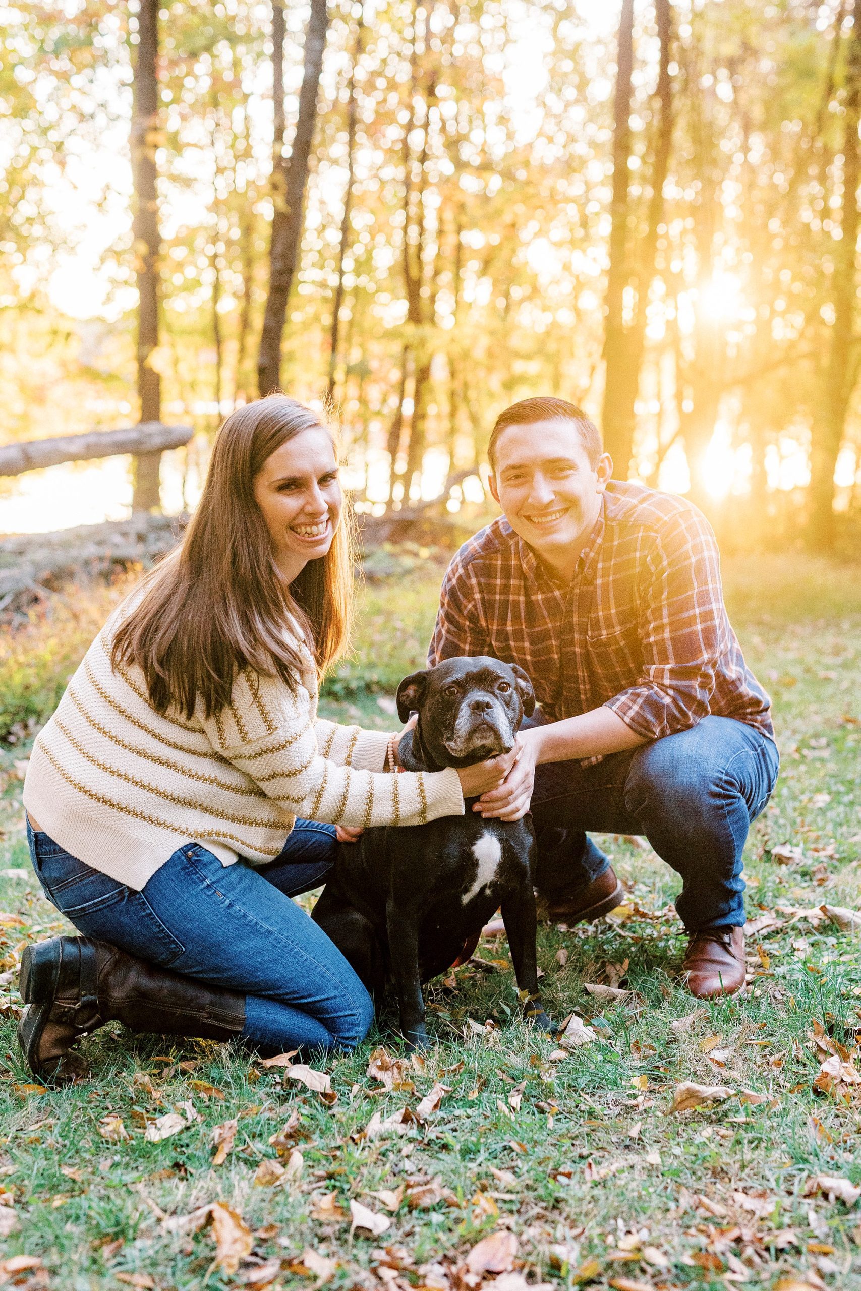 couple kneels with black dog at sunset at Latta Nature Preserve
