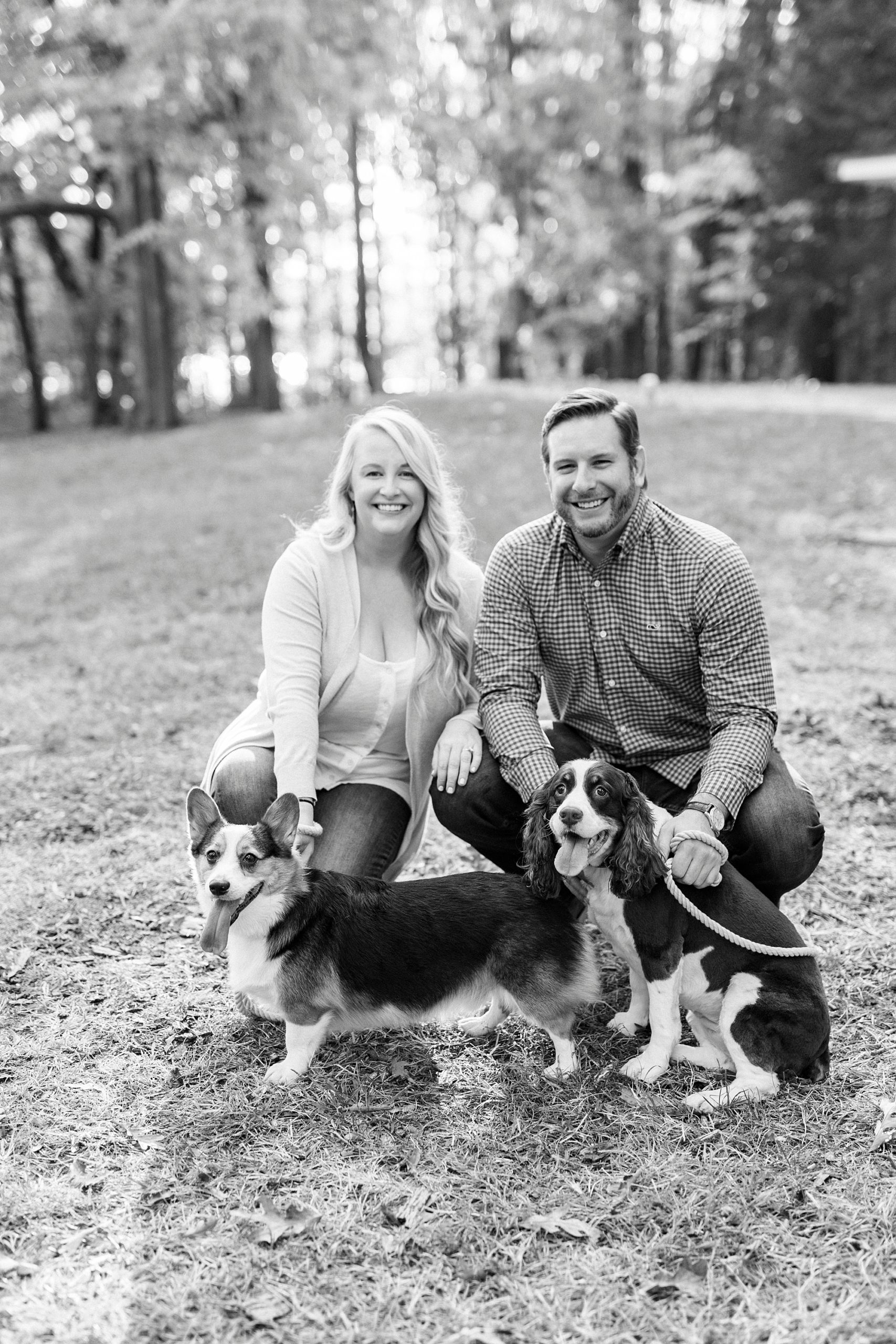couple leans down with dogs during photos in Latta Nature Preserve