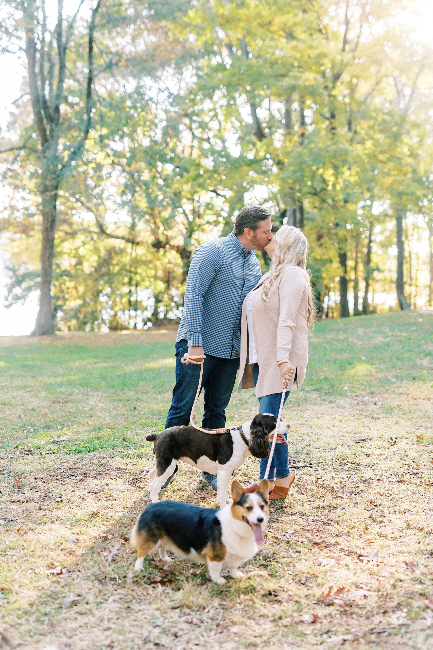 engaged couple kisses while walking dogs at Latta Nature Preserve