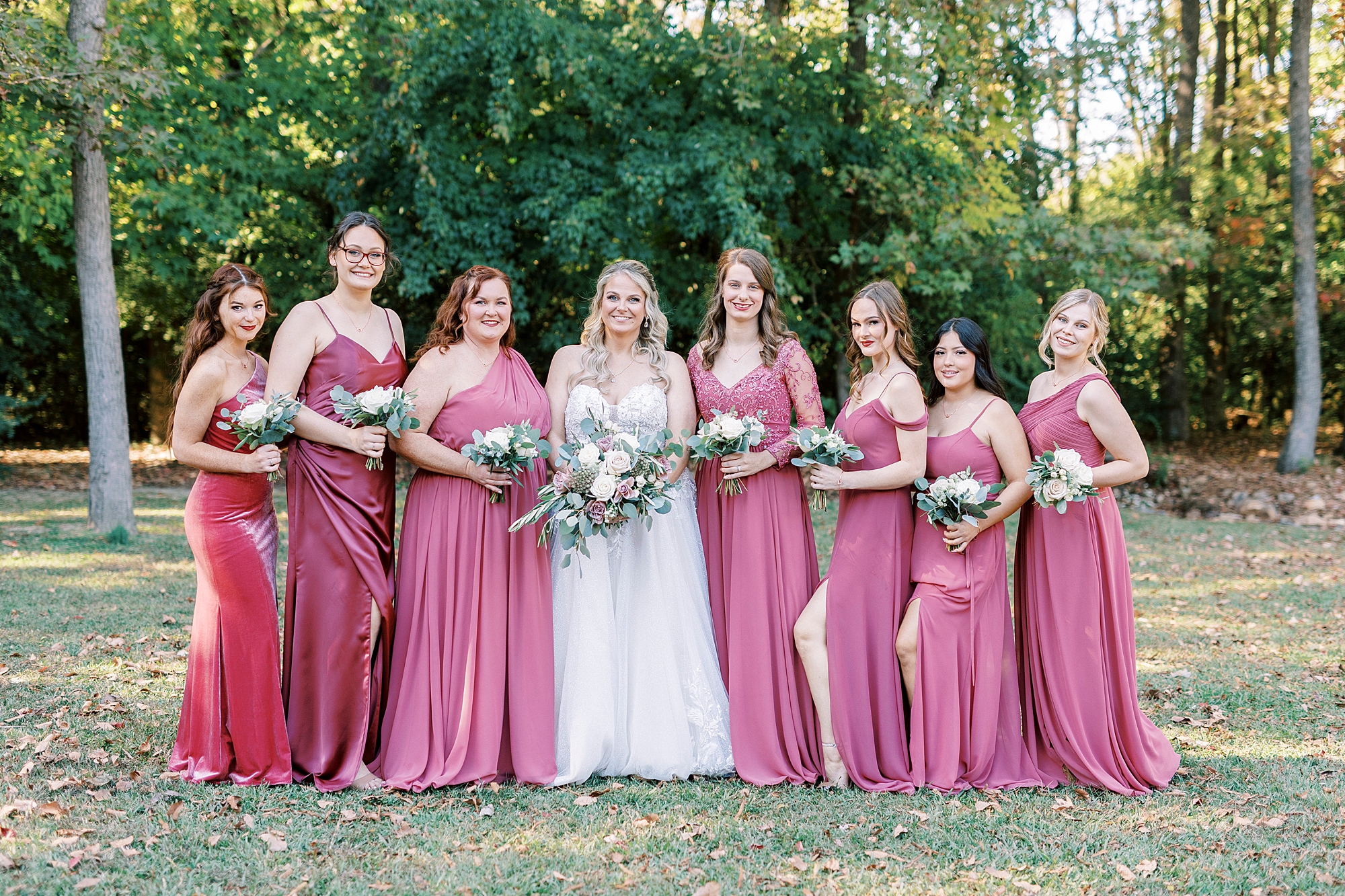 bride stands with bridesmaids in dusty pink gowns