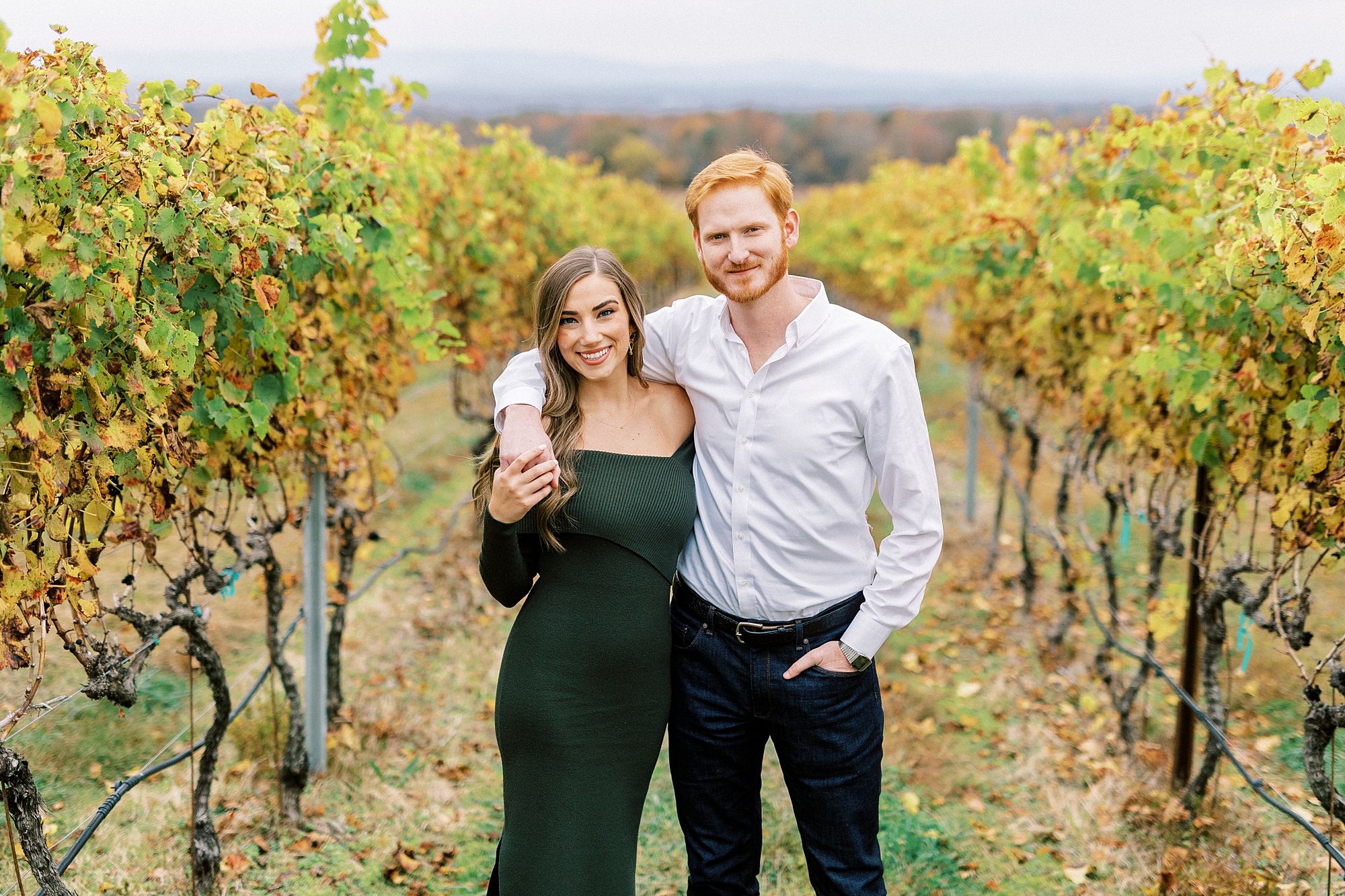 couple stands with arms around each other in vines 
