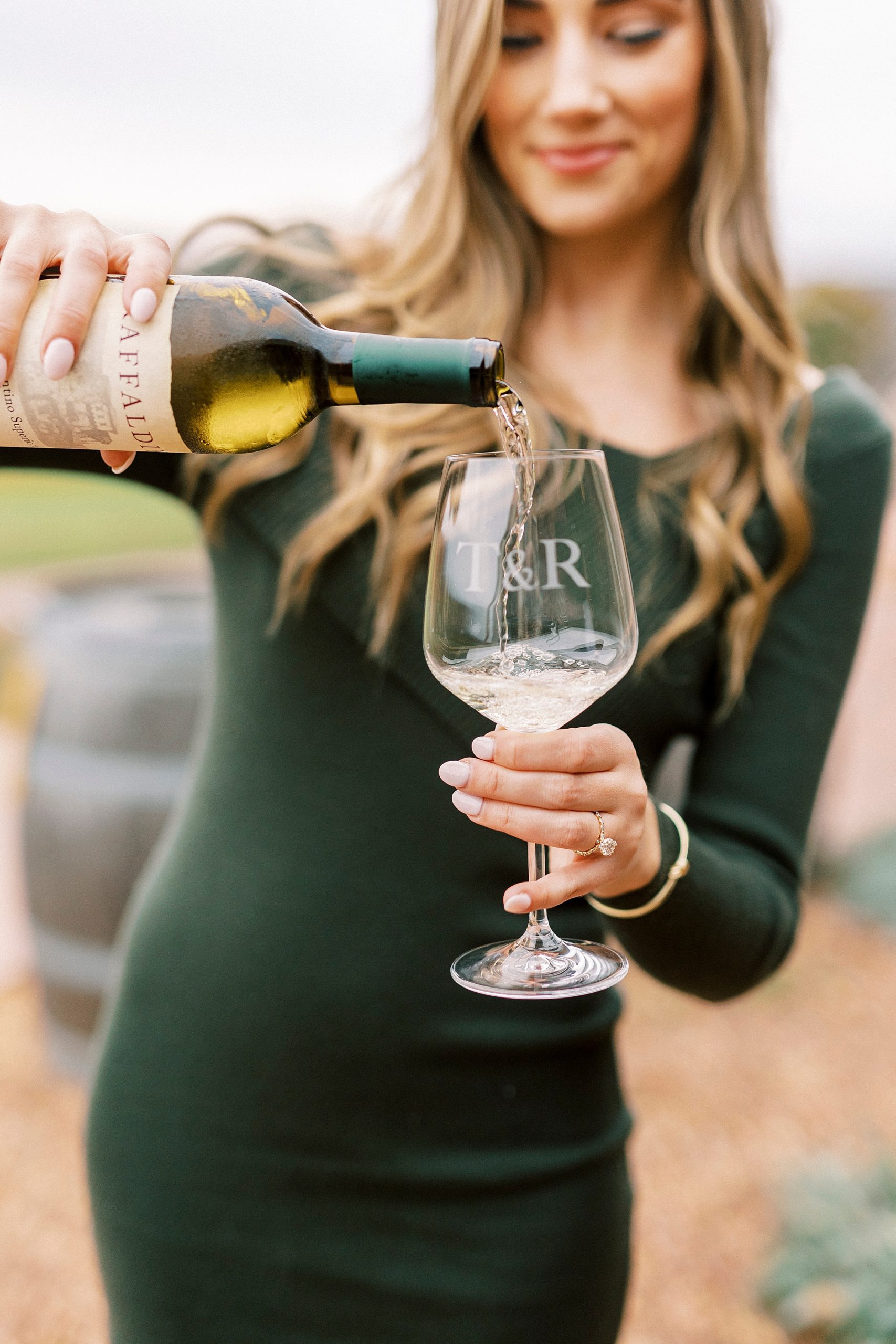 woman in chic green dress pours white wine into glass at Raffaldini Vineyards