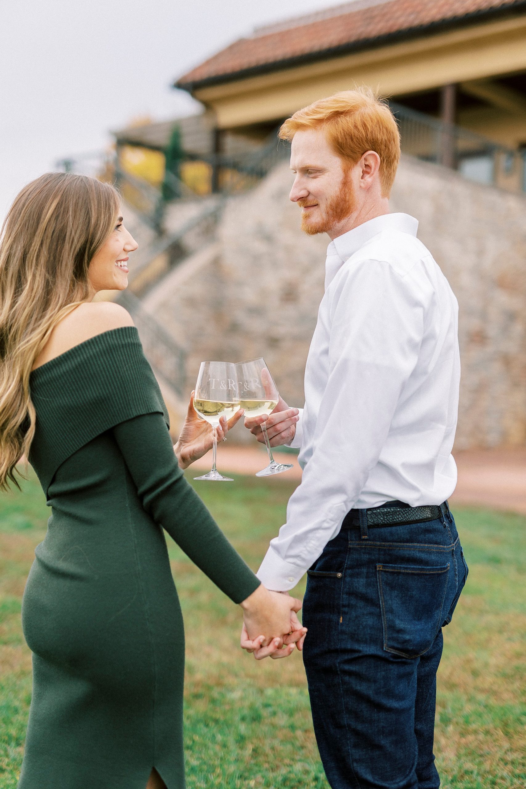 engaged couple laughs holding hands with wine at Raffaldini Vineyards