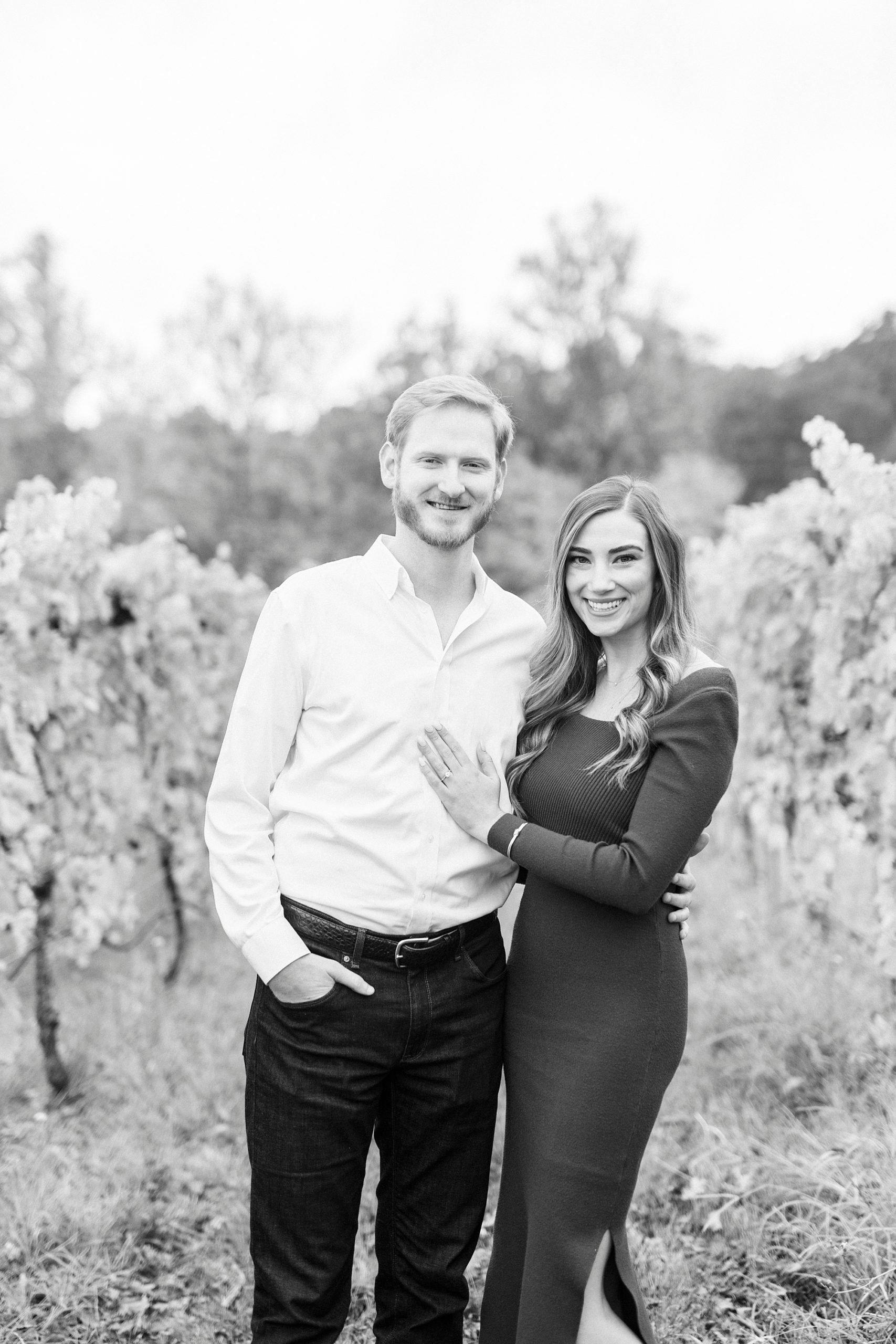 woman stands holding man's chest during fall engagement portraits 