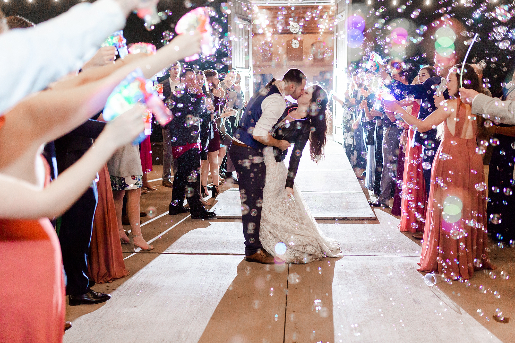 bride and groom kiss during bubble exit on wedding day