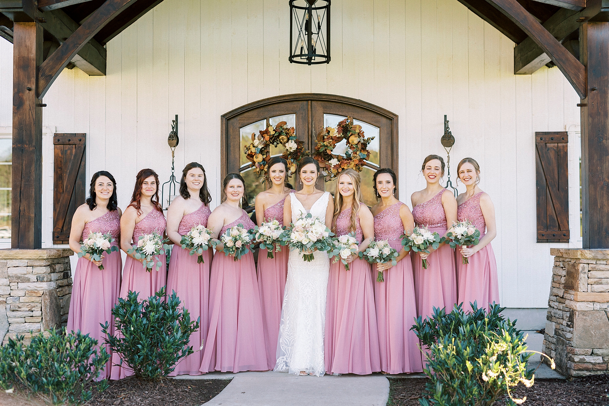 bride stands with bridesmaids in pink gowns outside Chickadee Hill Farms