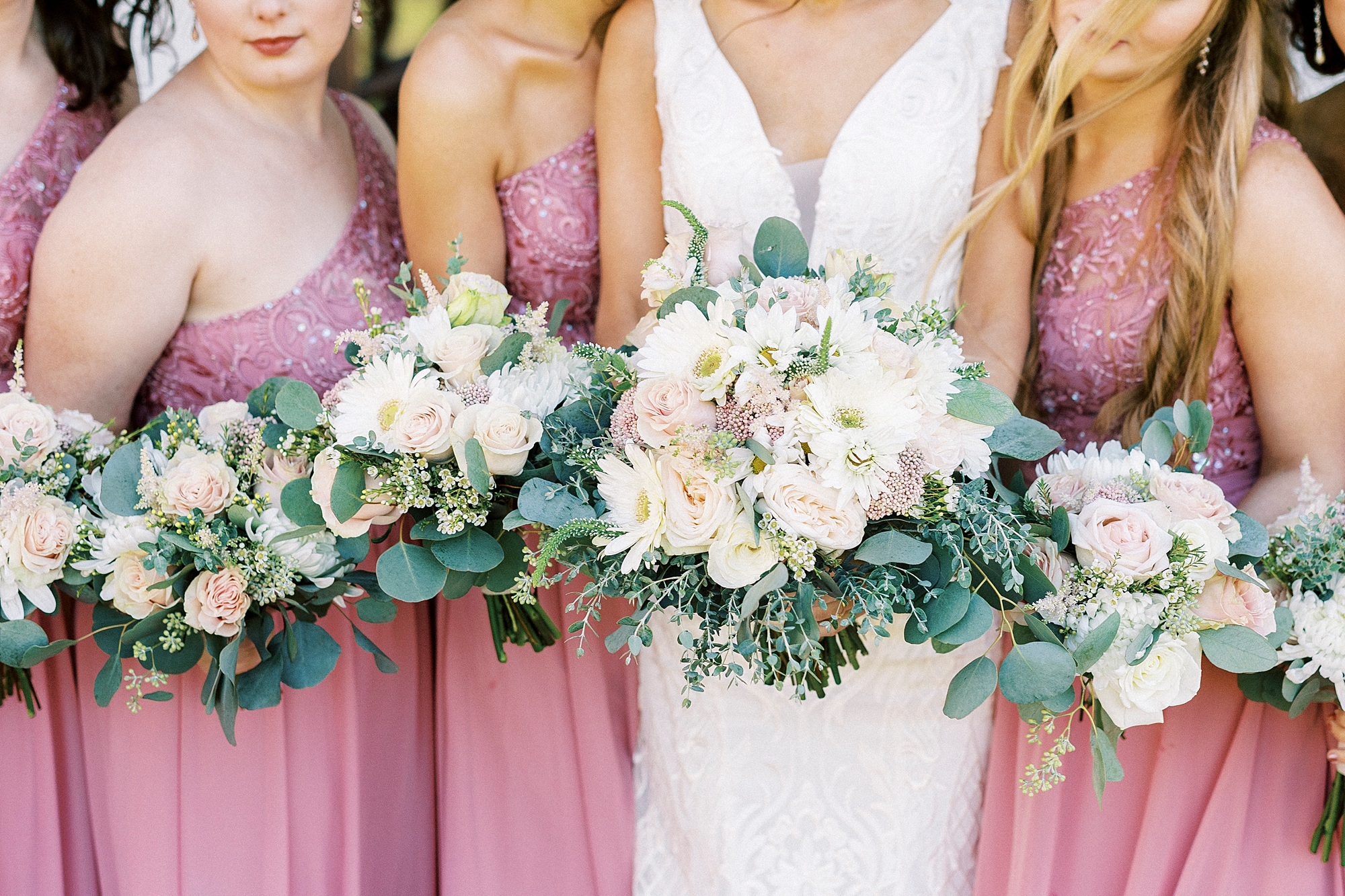 bride and bridesmaids huddle together holding pink and ivory bouquets at Chickadee Hill Farms