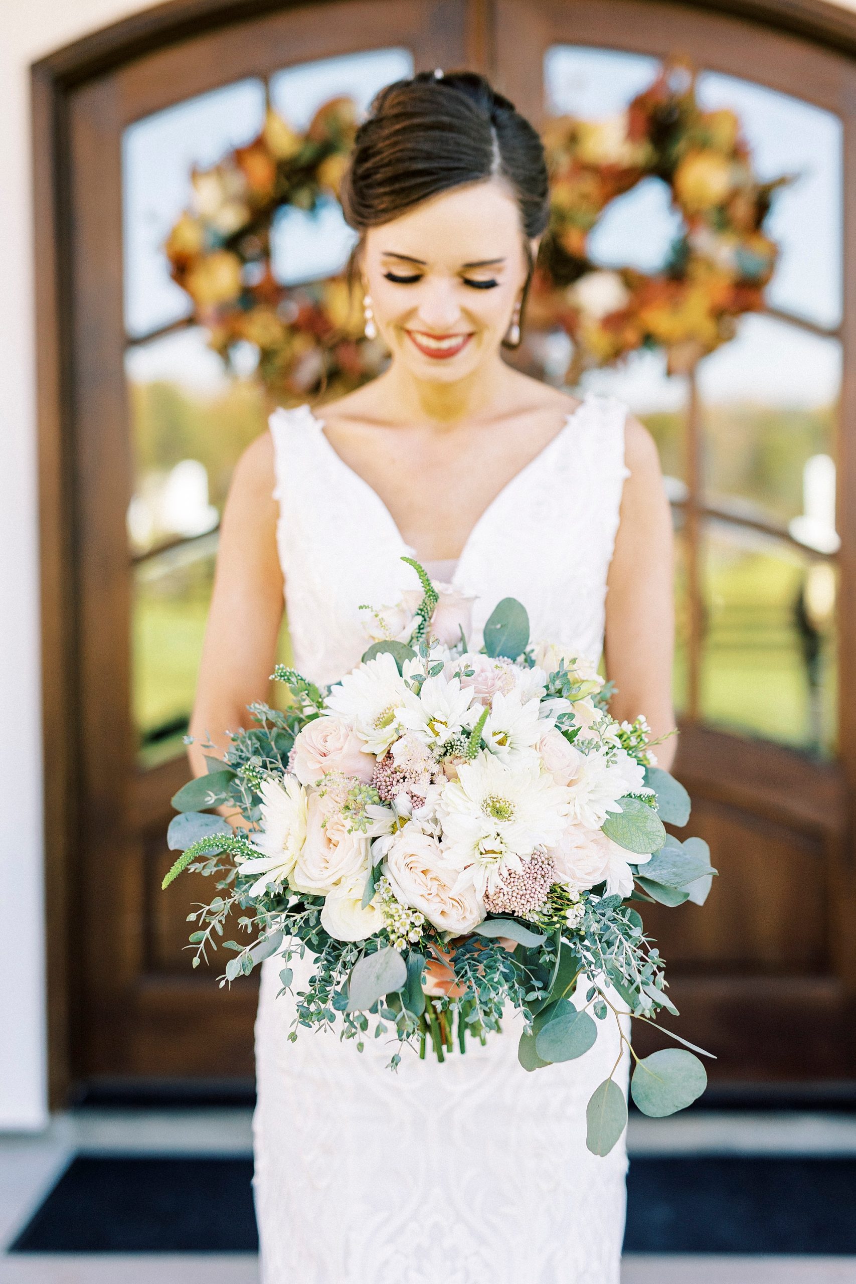bride poses outside Chickadee Hill Farms with pink and white bouquet 