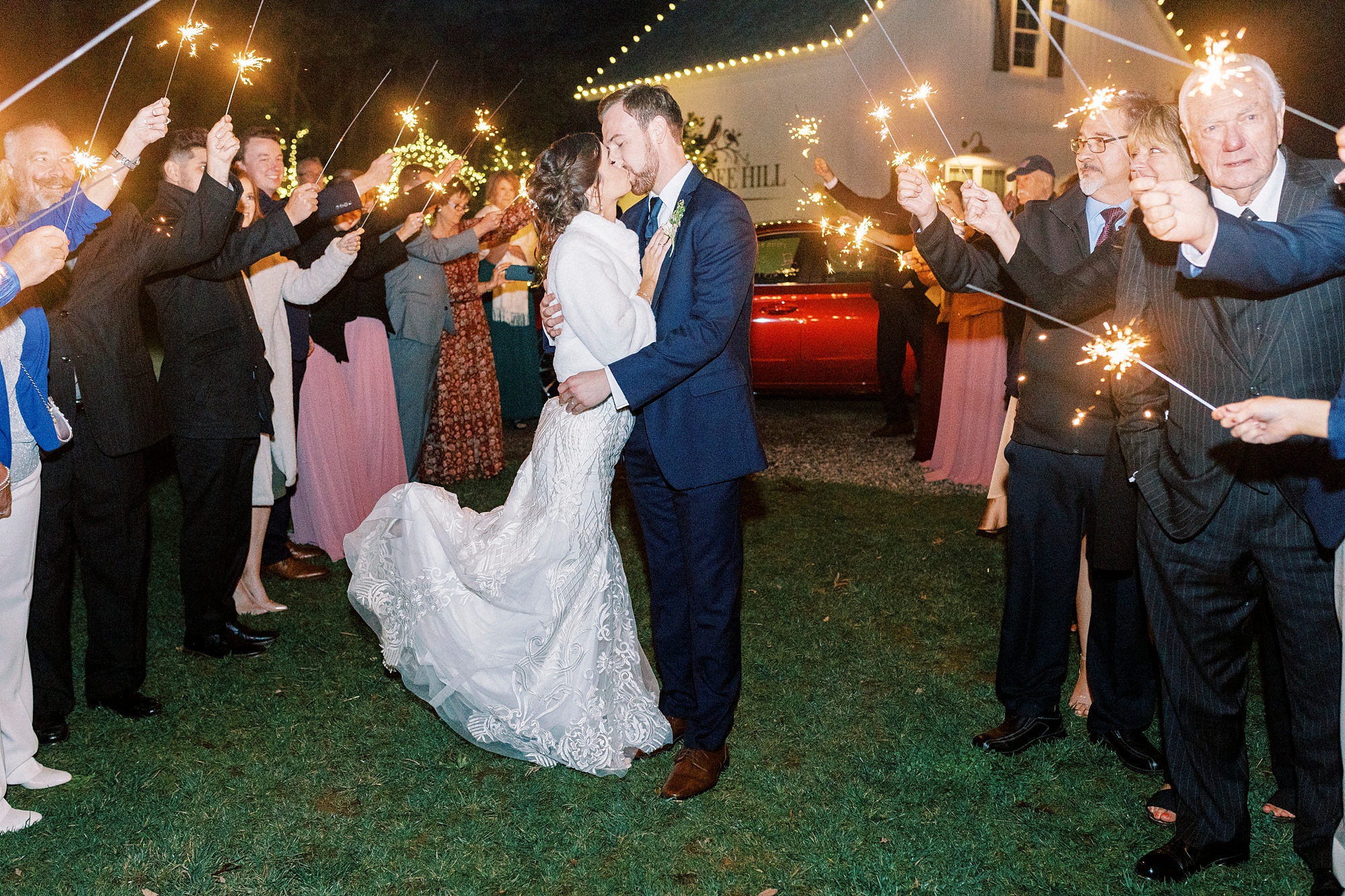 bride and groom kiss in sparkler exit while bride pops foot 
