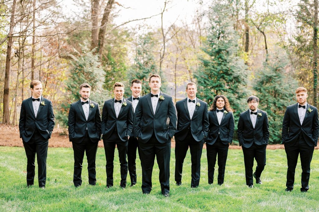 groom walks with groomsmen on lawn at the Hotel Concord 