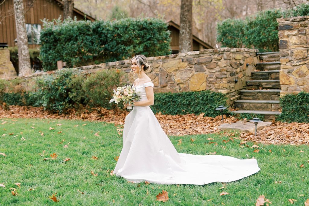 bride walks on lawn in off-the-shoulder wedding gown 