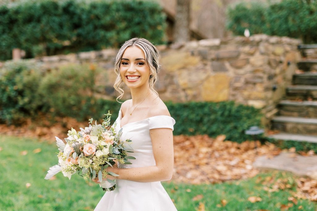 bride smiles holding pink, peach, and Ivory bouquet 