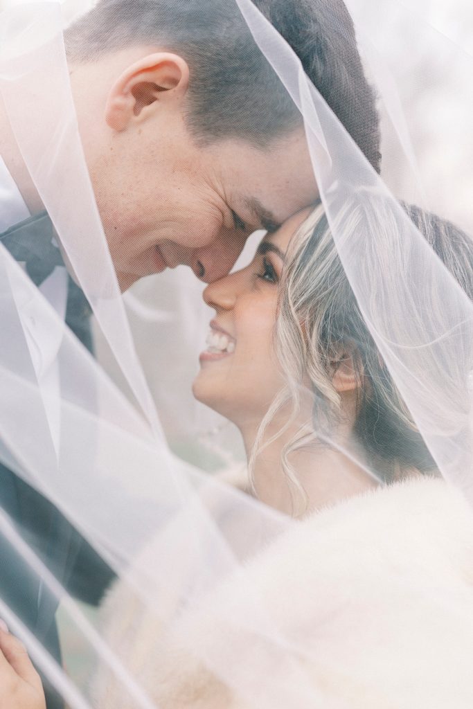 newlyweds smile together under bride's veil 