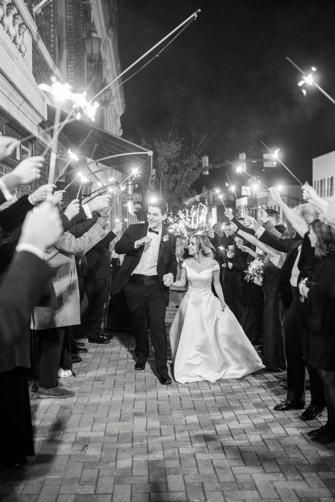 bride and groom hold hands walking through sparkler exit from the Hotel Concord wedding reception 
