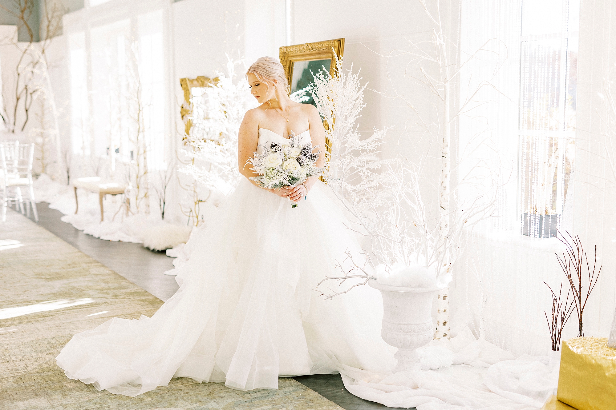 bride poses among white trees and accents for Winter Wonderland wedding at River Run Country Club