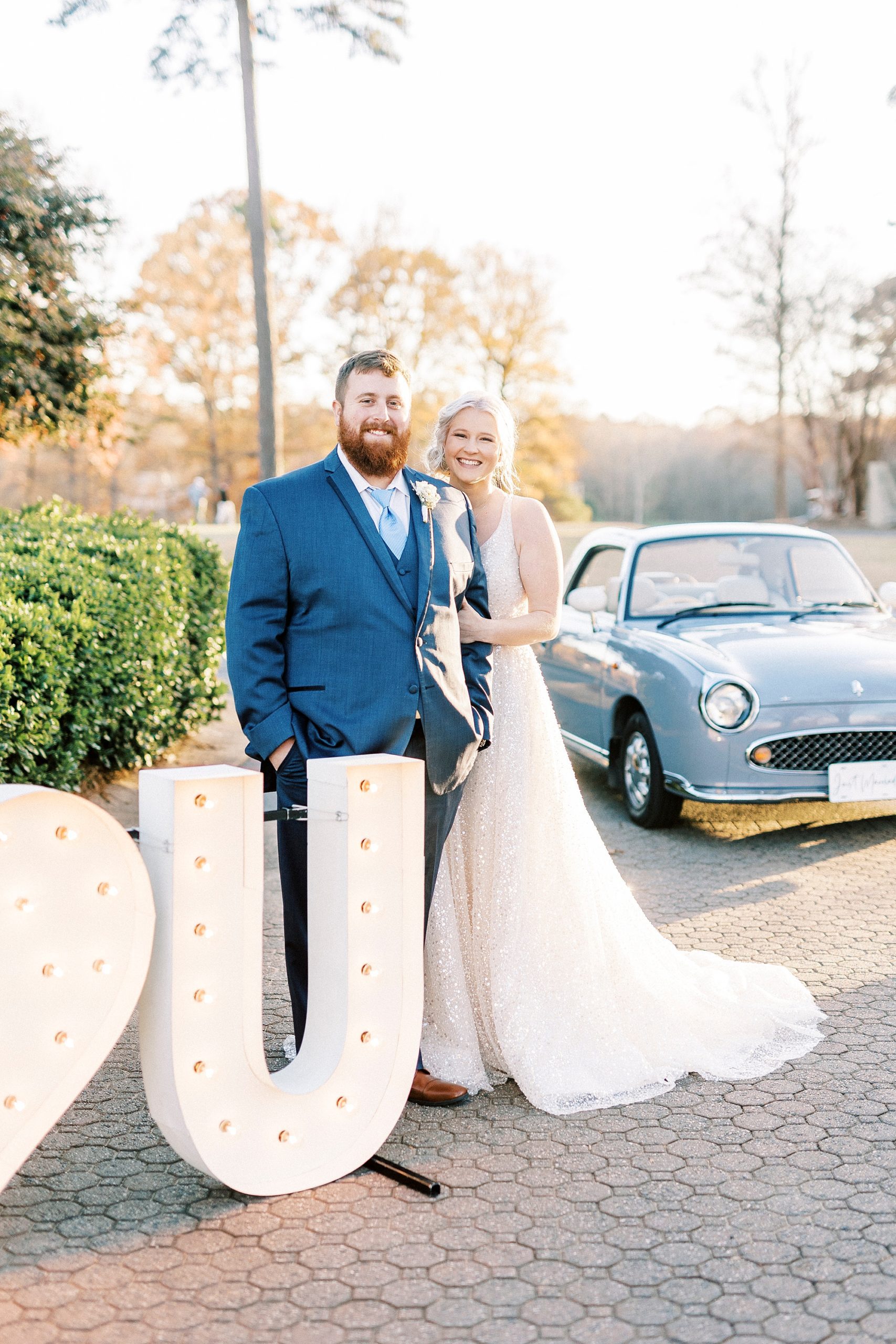 bride and groom hug by marquee letters and purple Charlotte the Figgy car 
