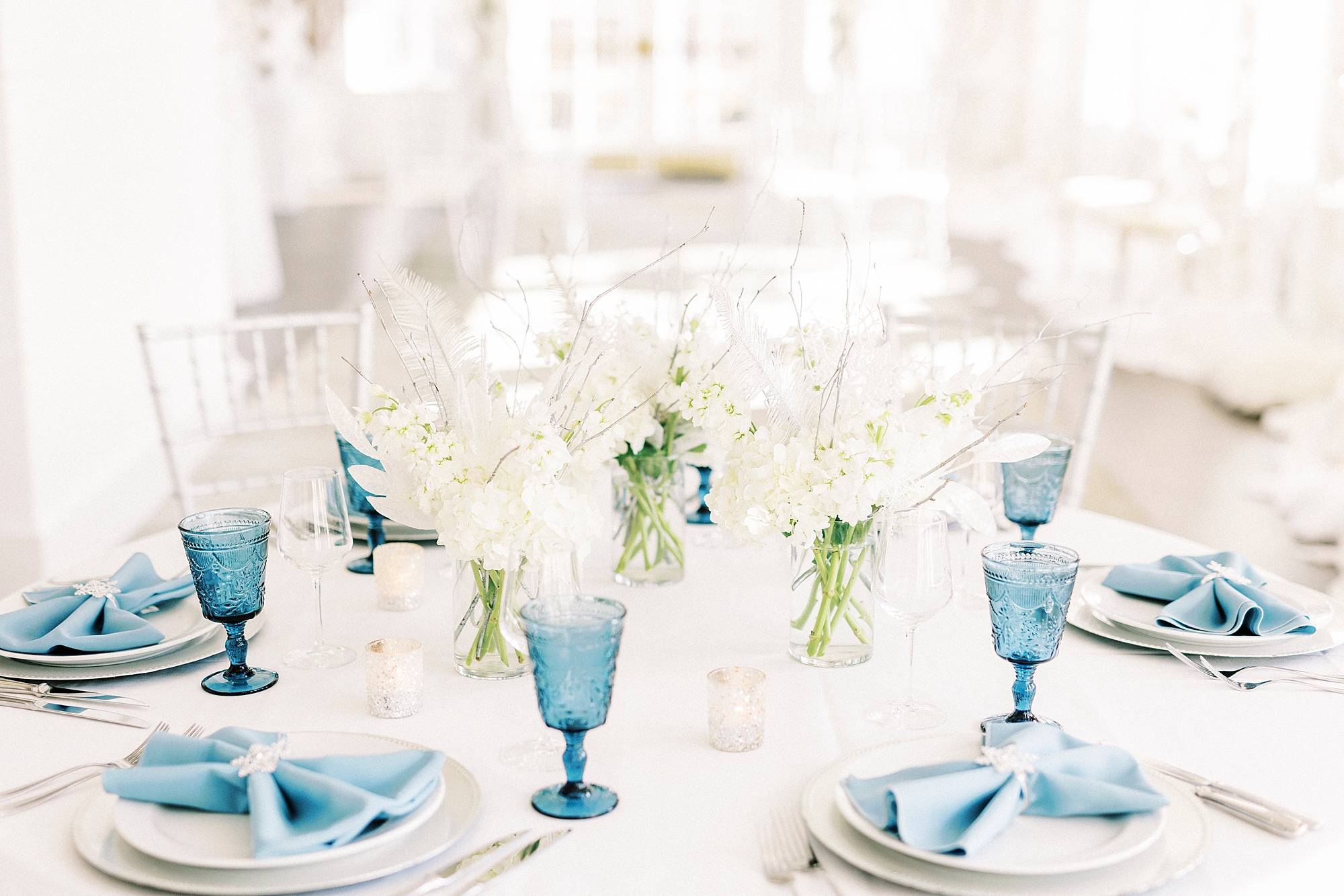 place settings with blue glasses and napkins for Winter Wonderland wedding at River Run Country Club