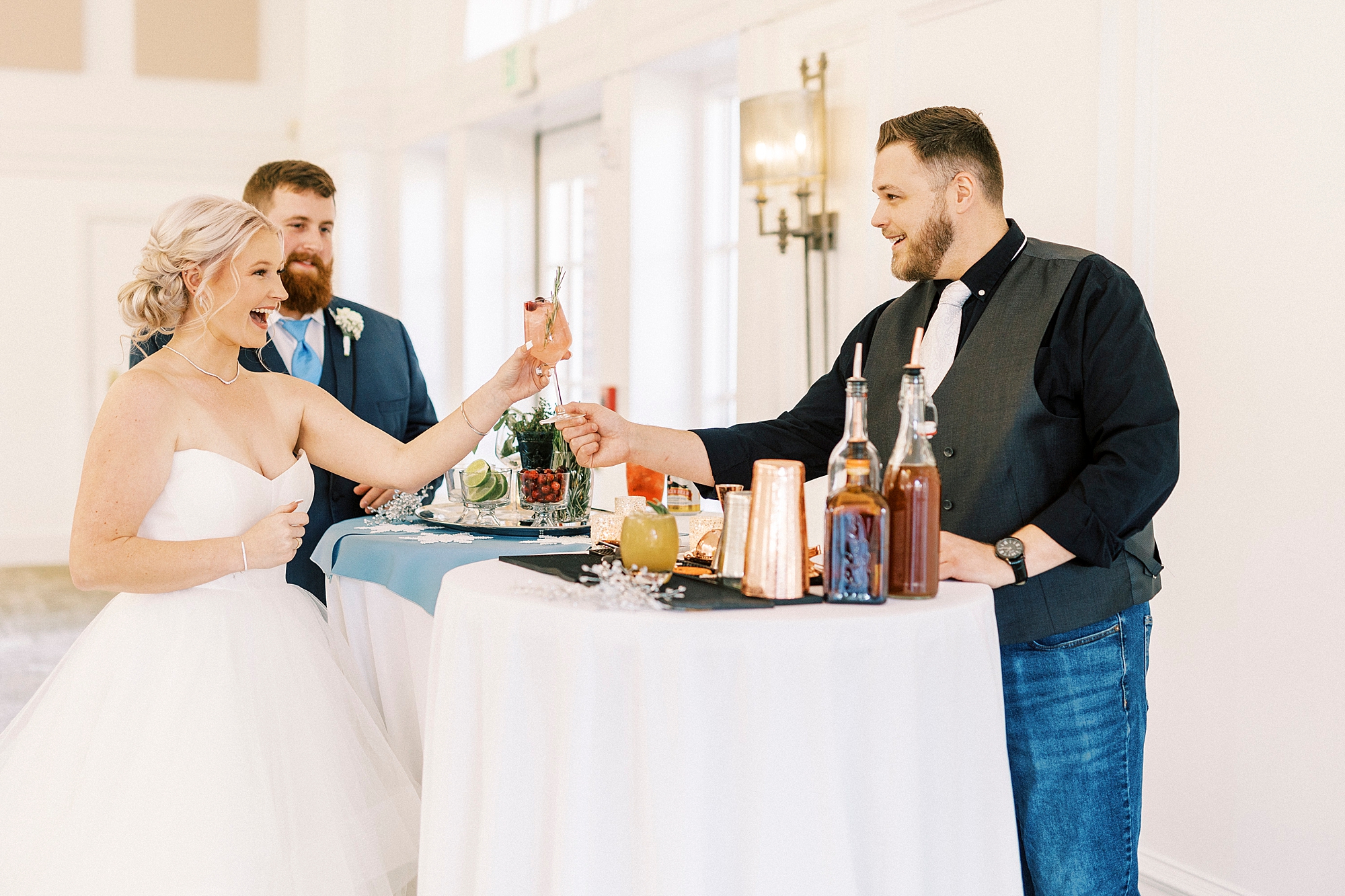 bartender gives couple drink during winter wonderland wedding at River Run Country Club