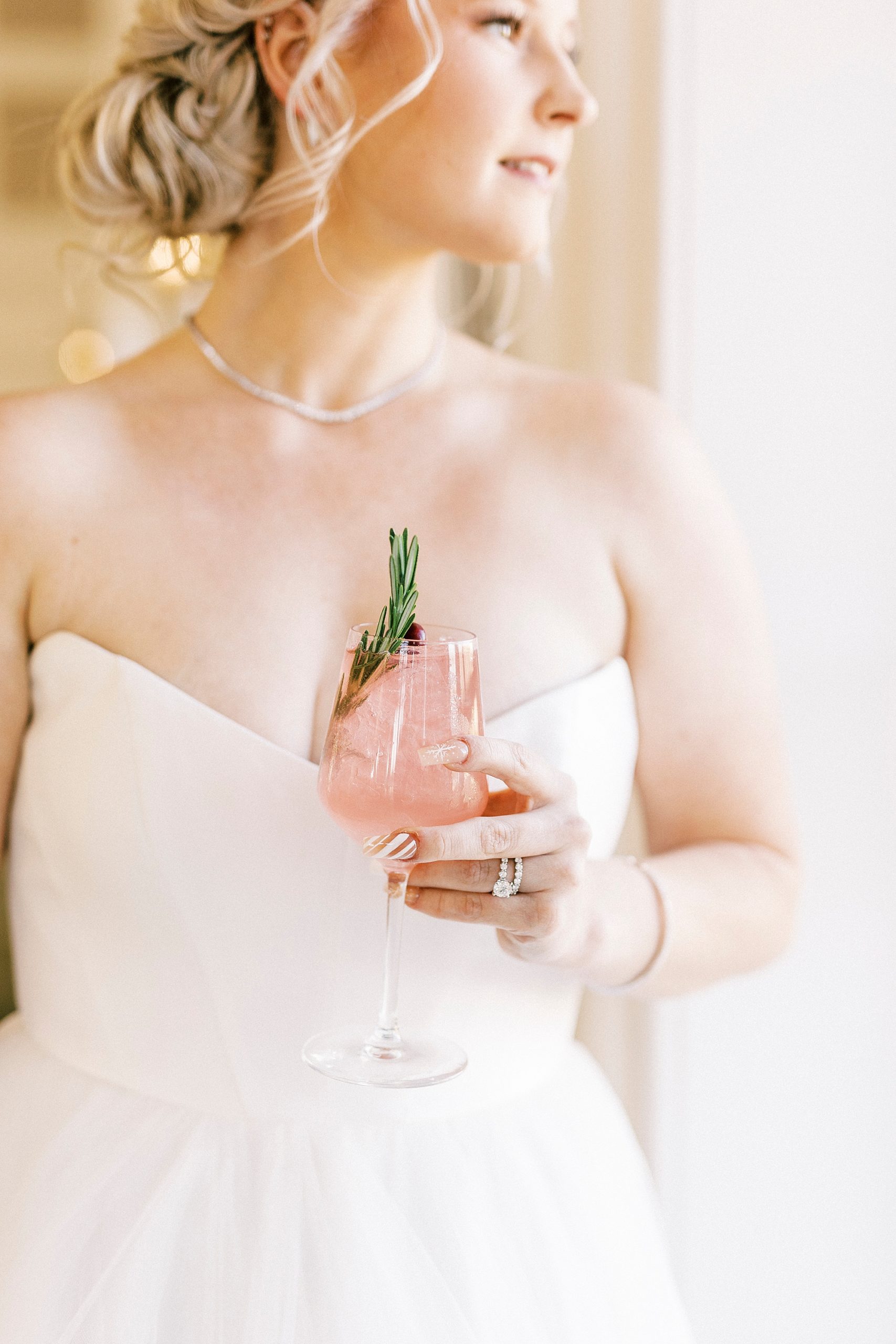 bride holds pink drink during winter wonderland wedding at River Run Country Club