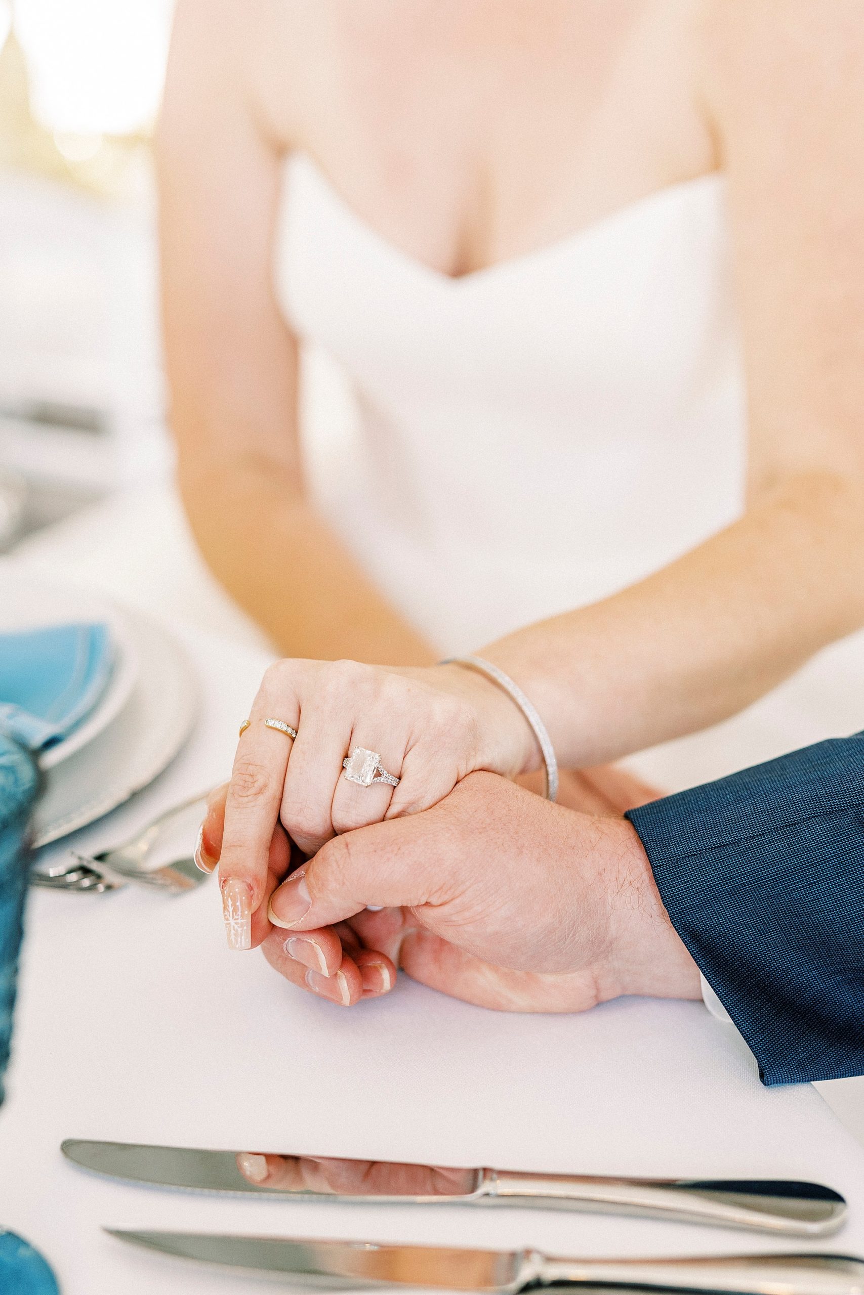 bride and groom hold hands on table during reception 