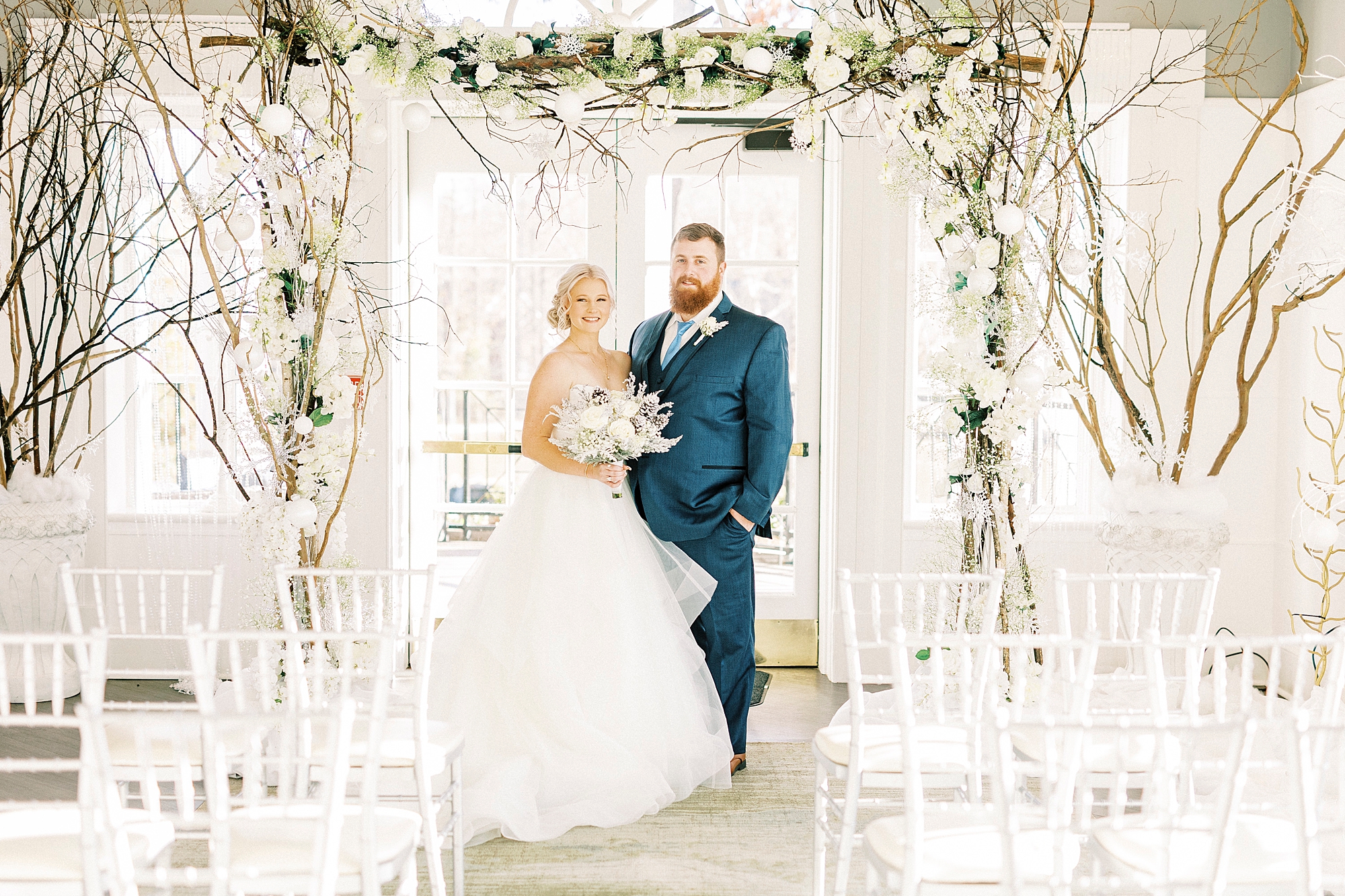 newlyweds pose under arbor for winter wonderland wedding at River Run Country Club