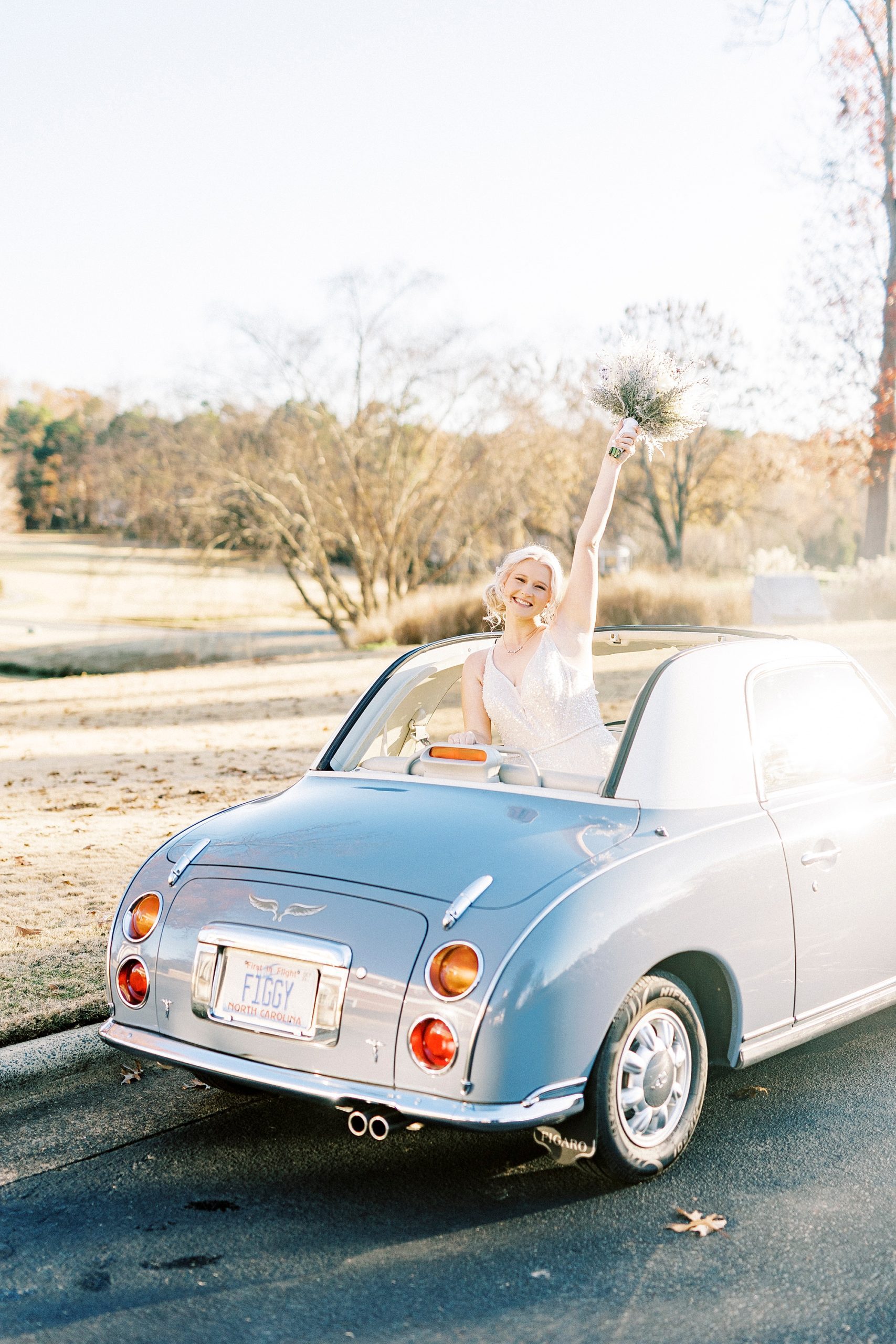 bride waves holding bouquet with pinecone accents in the back of Charlotte the Figgy