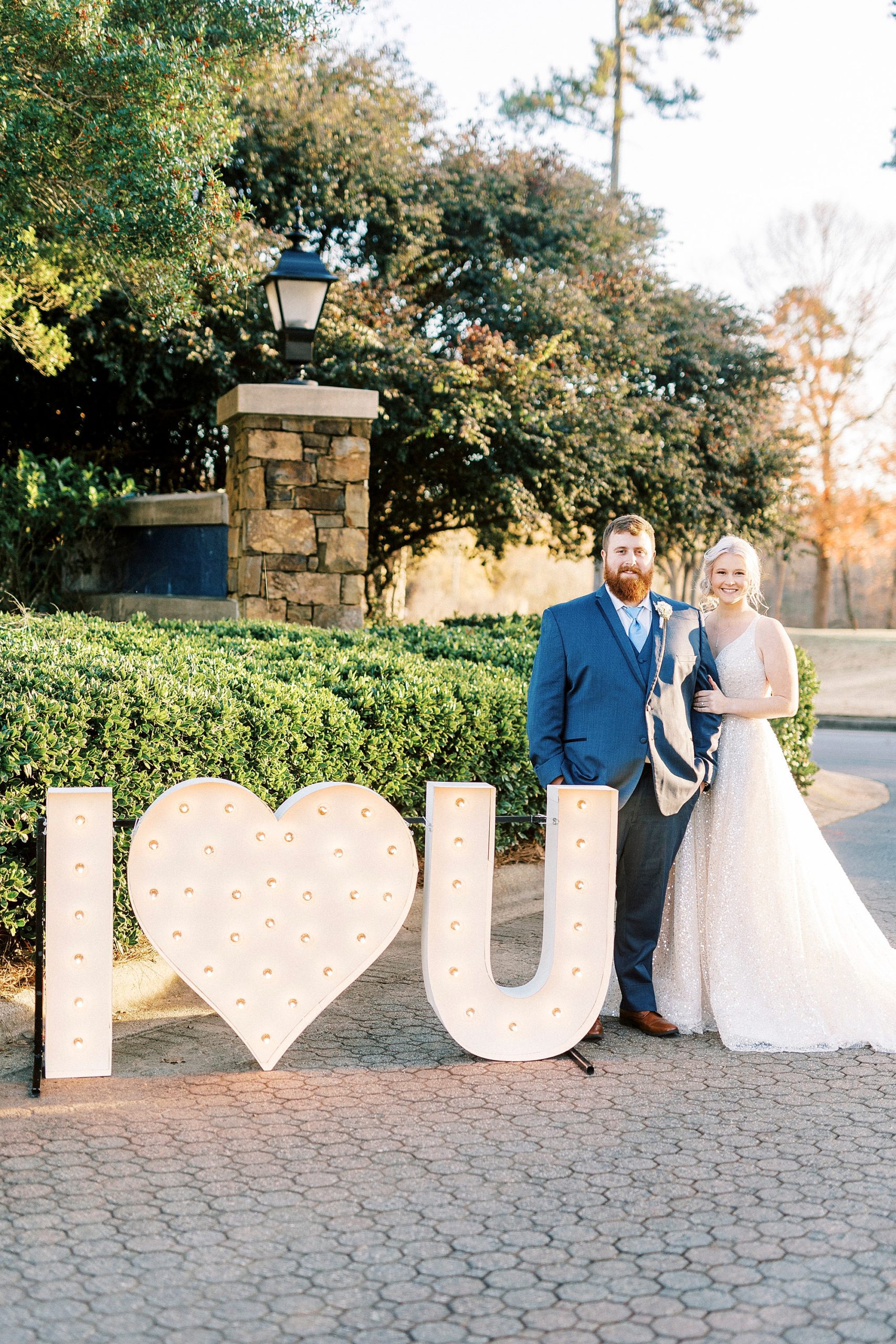 newlyweds pose by marquee lights outside River Run Country Club 