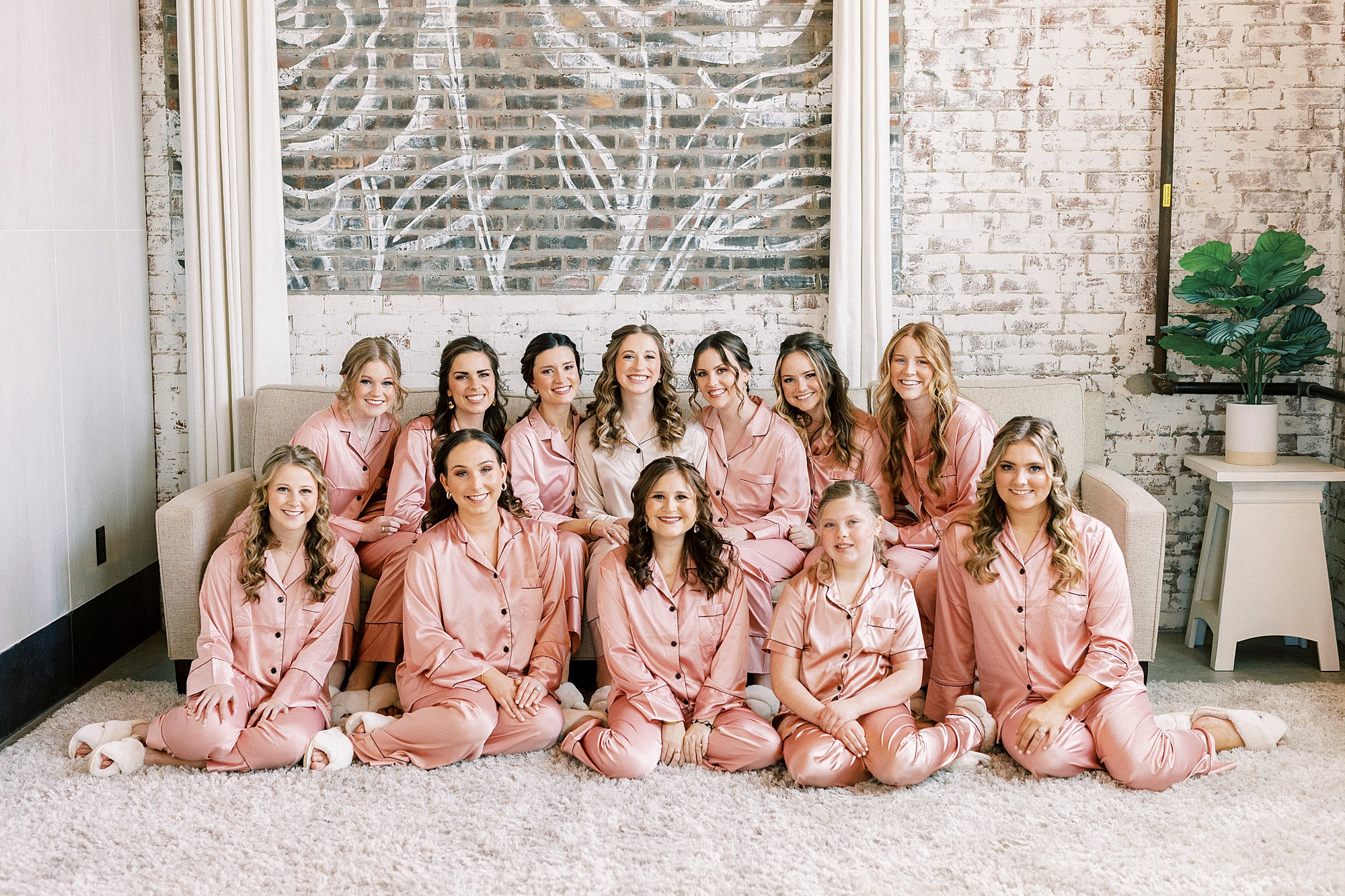 bride sits with bridesmaids in matching pink robes 