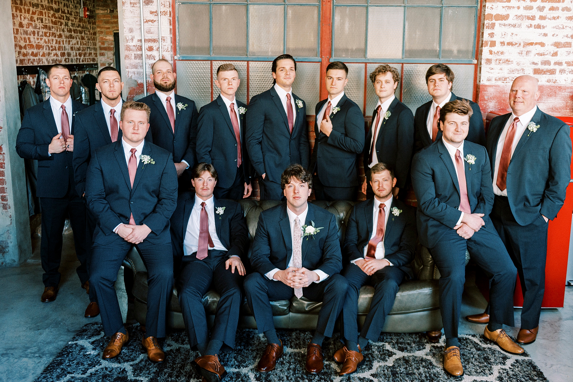 groom sits with groomsmen in navy suits with pink ties 