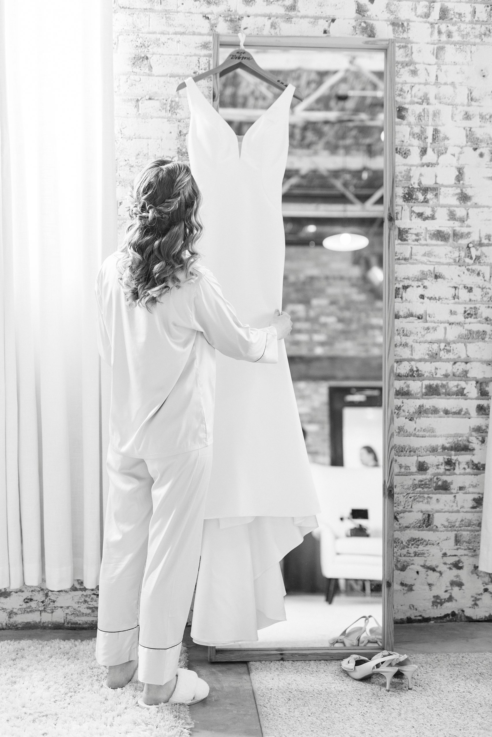bride looks at wedding gown hanging at the Cadillac Service Garage 