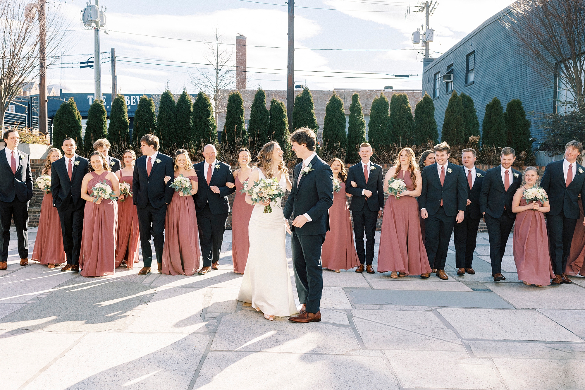 bride and groom stand with wedding party on patio at Cadillac Service Garage