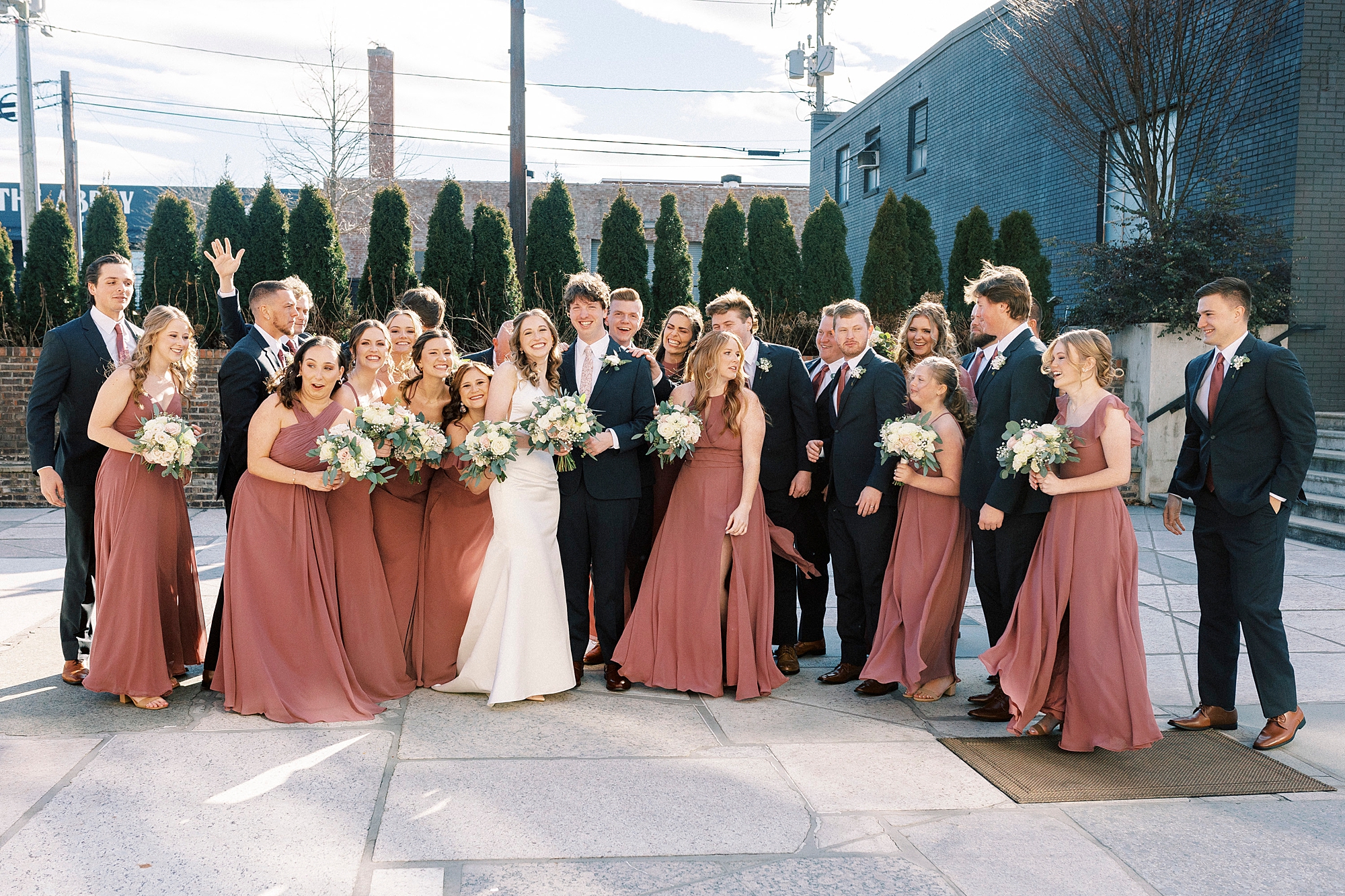 newlyweds stand with wedding party on patio at the Cadillac Service Garage