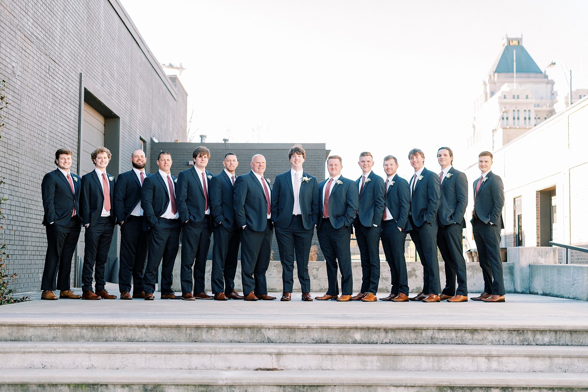 groom poses with groomsmen in navy suits at Cadillac Service Garage