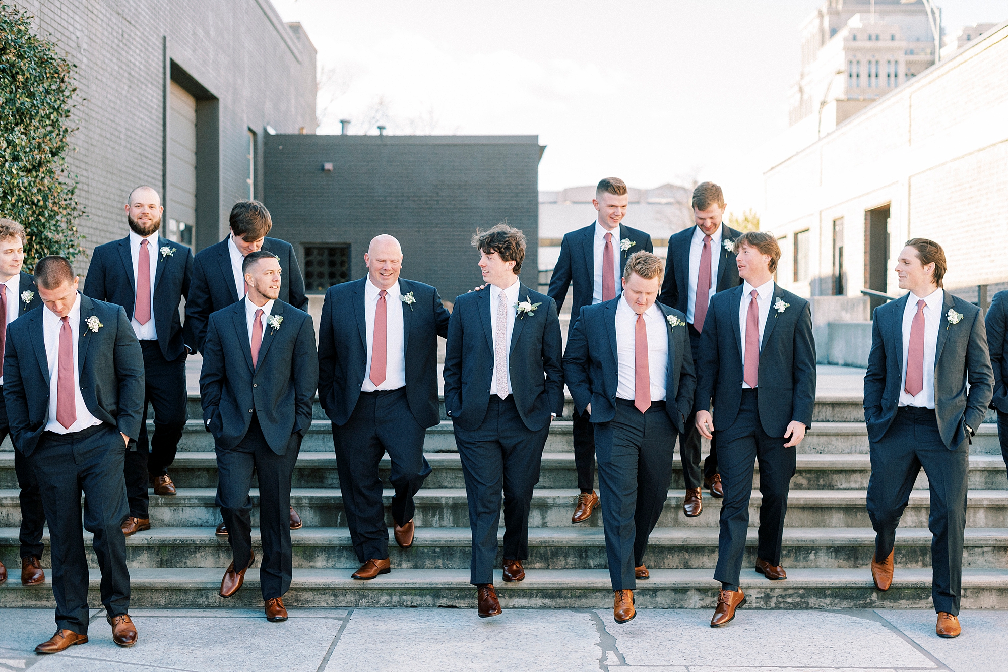 groom walks down steps with groomsmen in navy suits at the Cadillac Service Garage