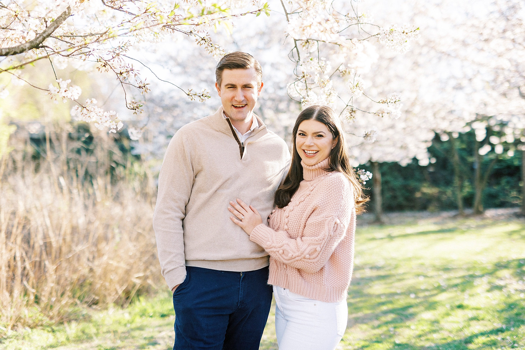 couple poses by cherry blossoms in Elizabeth Park during spring engagement photos 