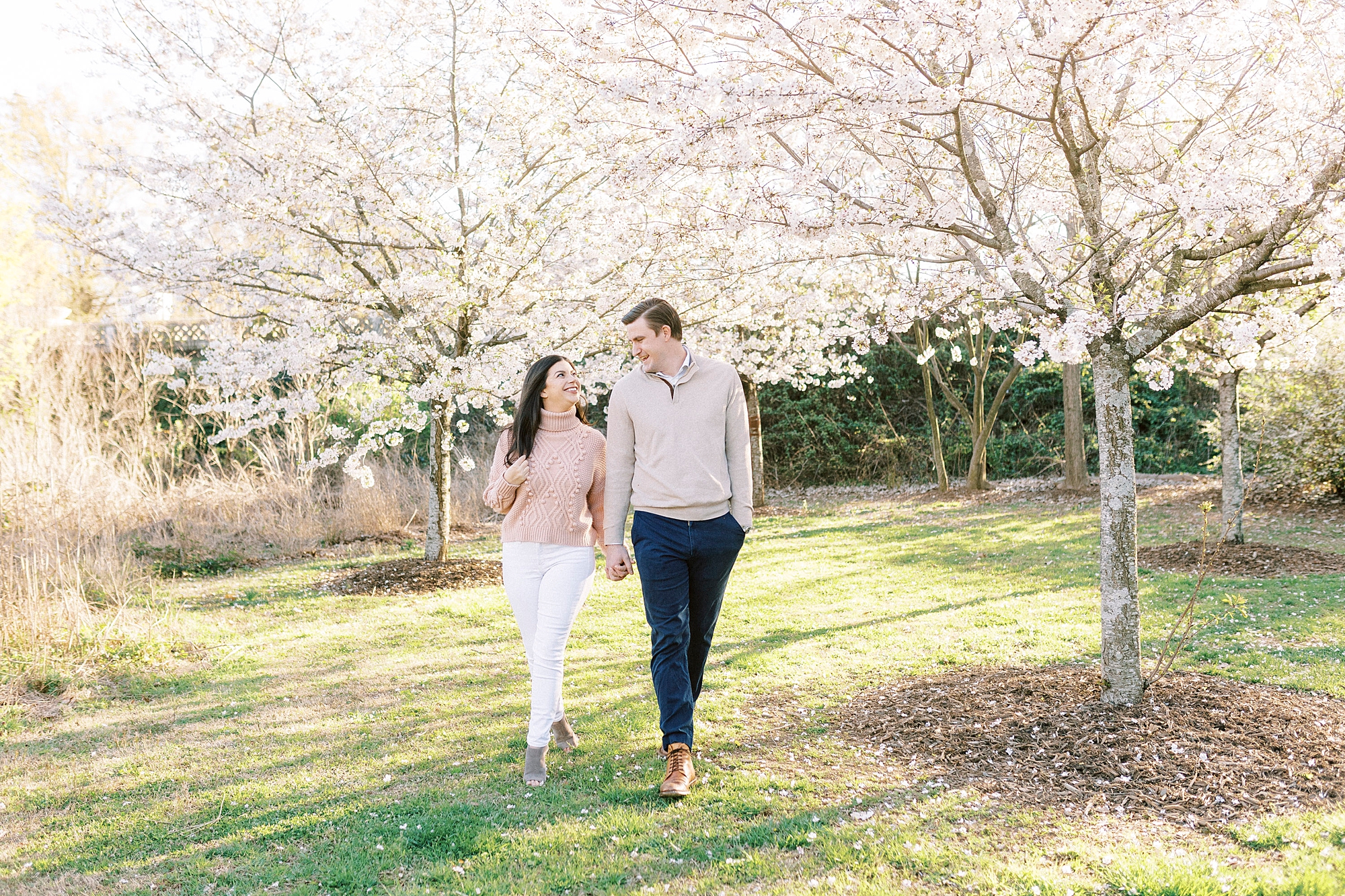engaged couple walks together through patch of trees